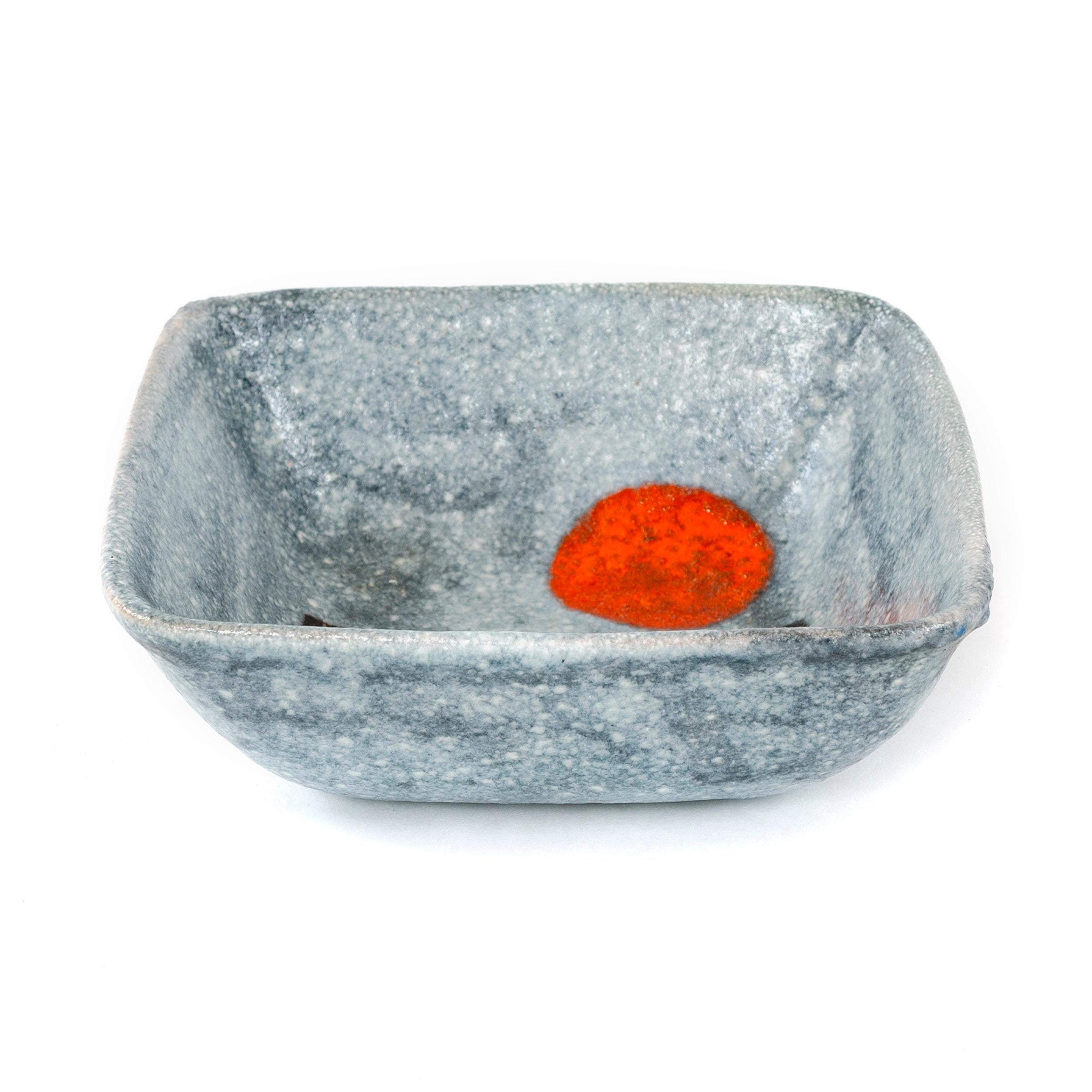 Proportionately deep walled ceramic bowl in a light gray glaze with contrasting decoration consisting of brightly colored geometric shapes. Donkey signed on back.