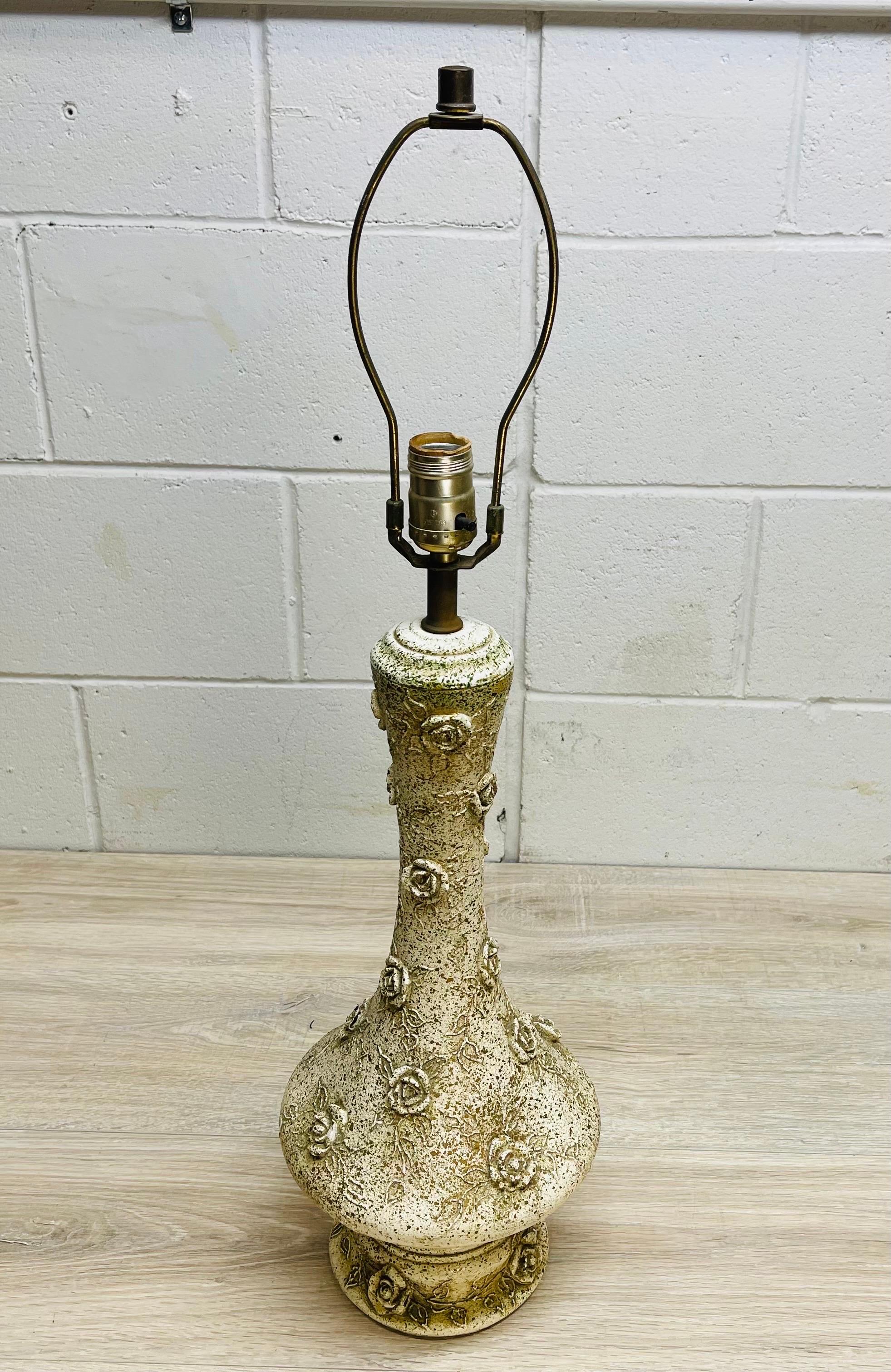 Vintage 1950s ceramic table lamp with a rose design. The lamp is speckled green all over on an off-white base. Wired for the US and in working condition. The lamp uses a standard 100W bulb. Socket, 22”H. Harp, 4”Dia x 8”H. No marks.