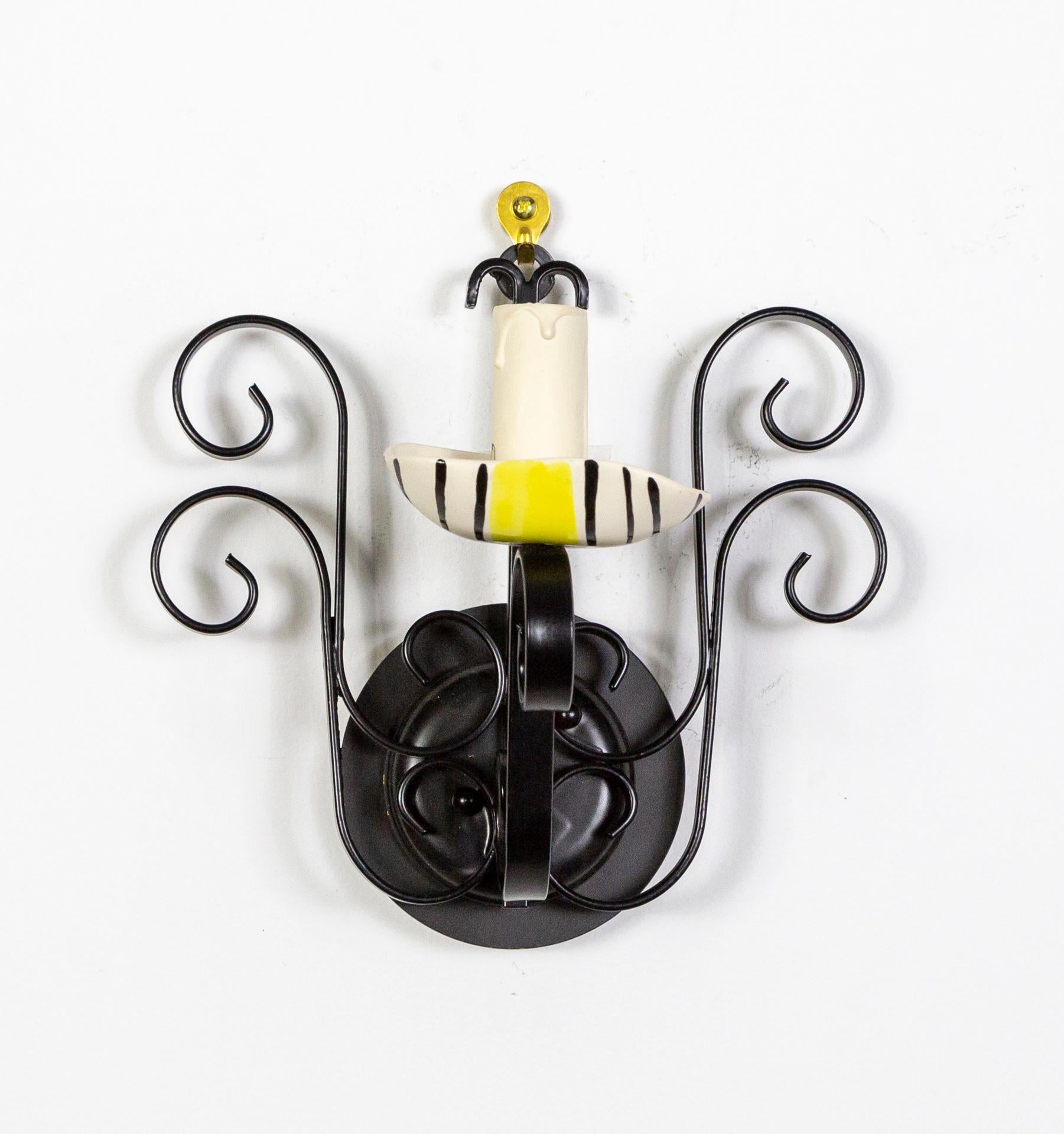 A set of 4 collectible wall lights by Ecole de Vallauris. Each sconce is composed of black-laquered wrought iron; with four S-curves on a circular backplate and a fifth holding an asymmetrical, handmade candle cup. Each bobeche is unique, hand