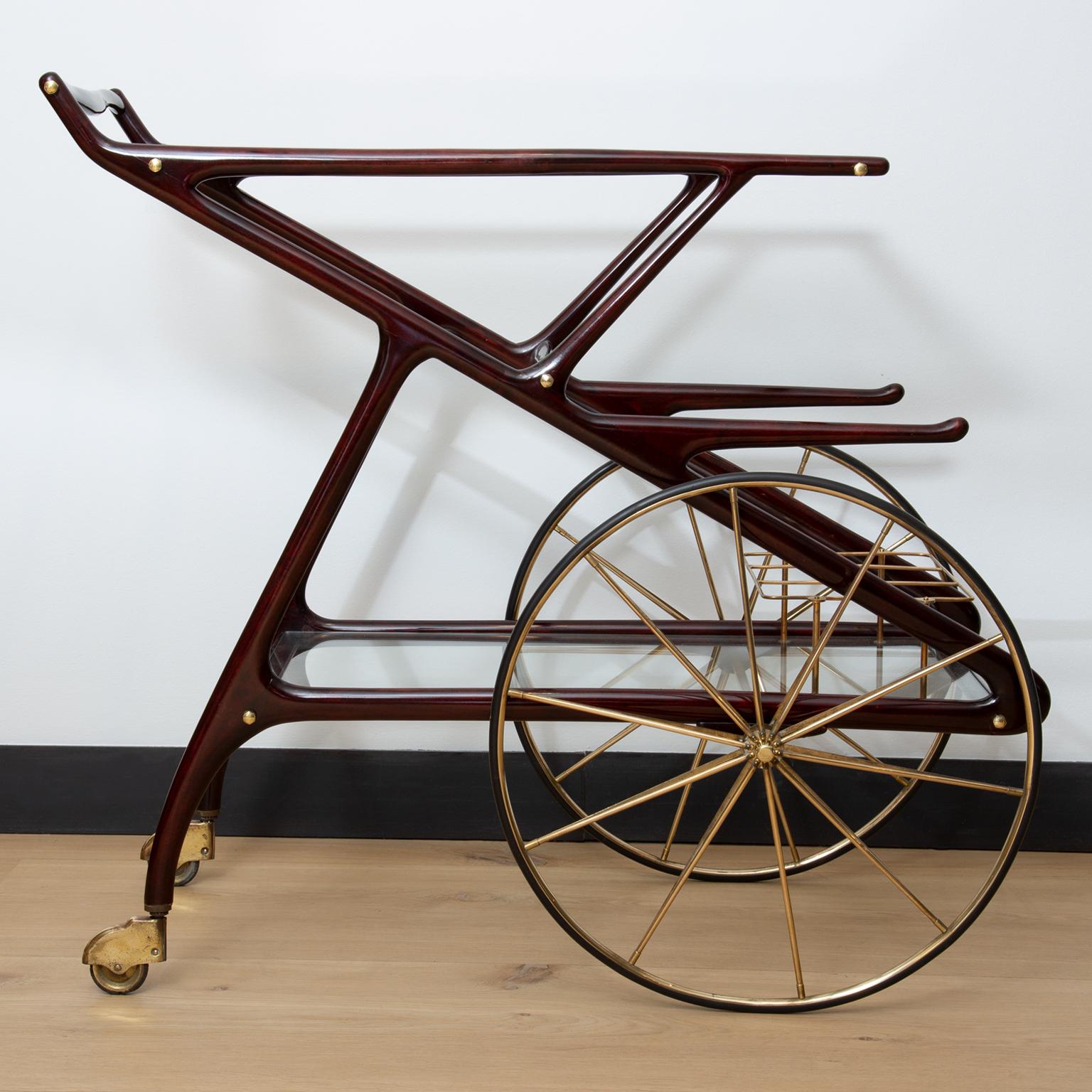 A large proportioned sculptural wood, brass and glass bar trolley designed by Cesare Lacca.