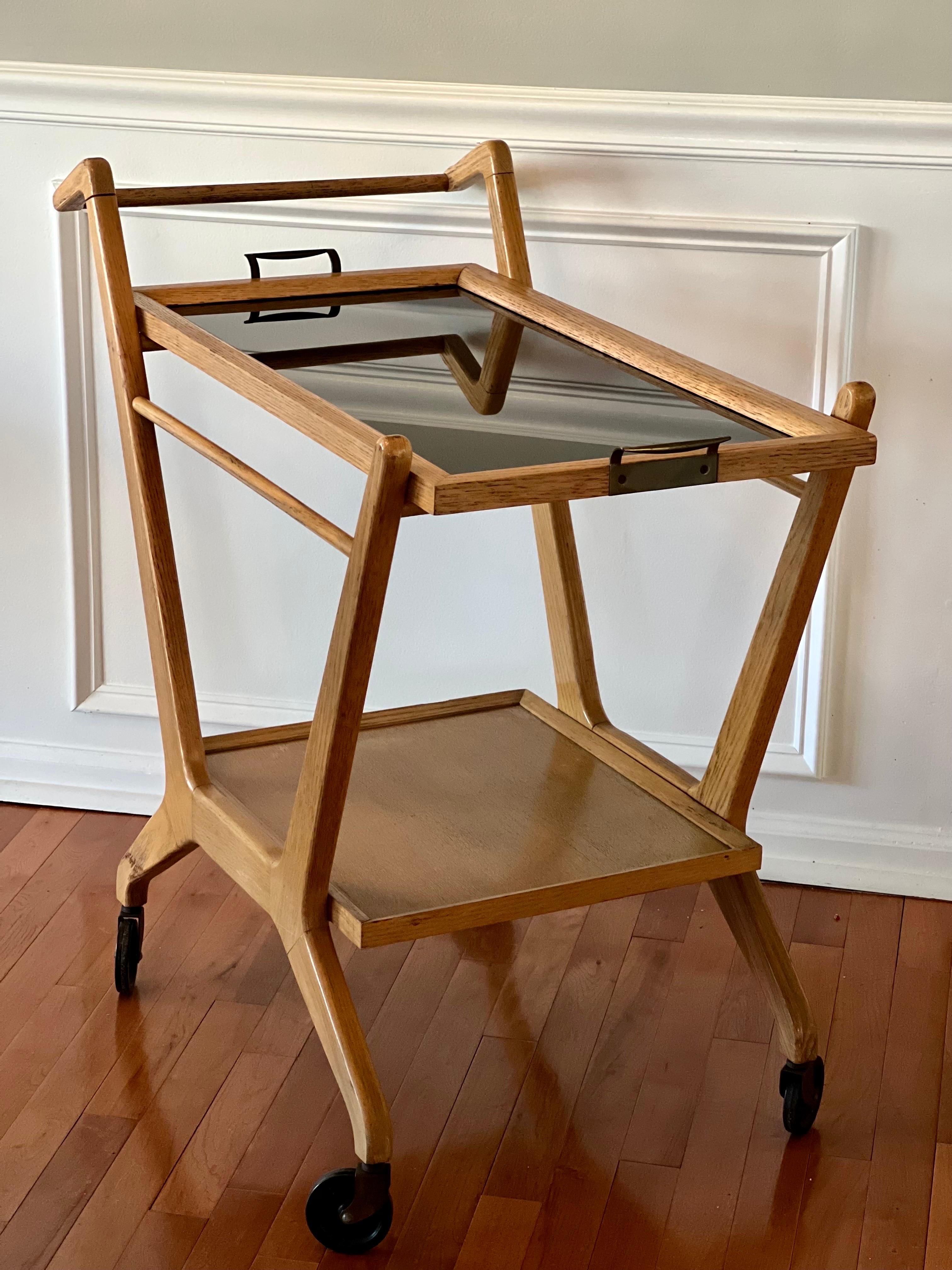 1950's Cesare Lacca golden oak bar cart for Cassina on casters. Original removable smoked glass tray is accented with brass handles. Beautiful and stylish Italian Mid Century design.