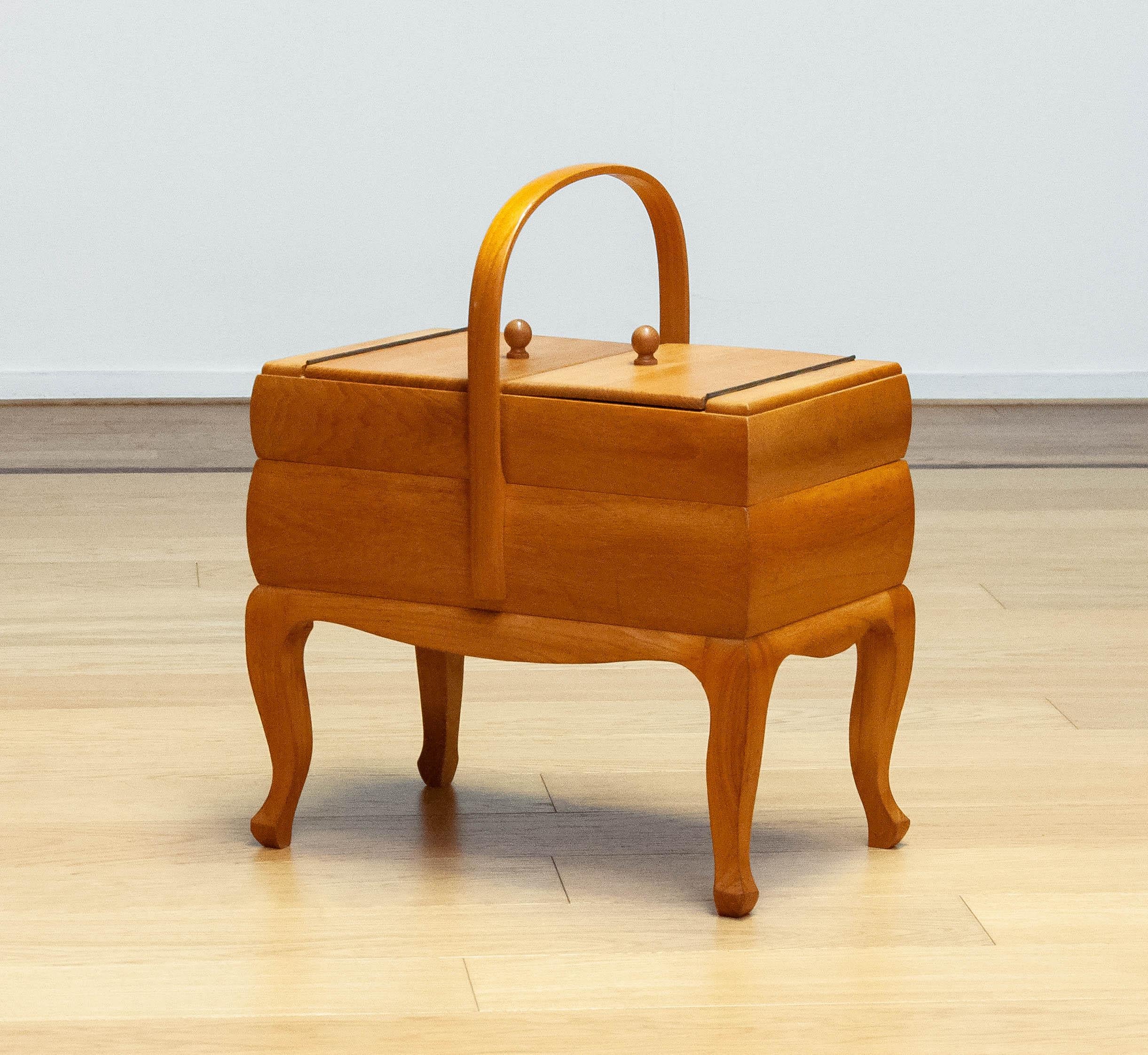 Charmante boîte à couture suédoise des années 1950, fabriquée en orme massif. Cette pièce à la fois pratique et décorative reflète la tradition scandinave qui consiste à combiner fonctionnalité et élégante simplicité. Les tons chauds et le grain