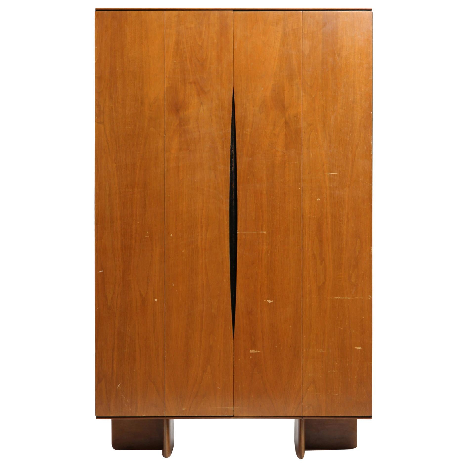 A Mid-Century Modern pale cherrywood wardrobe designed by Vladimir Kagan. This wardrobe has a rectilinear form with bi-fold doors with long distinctive Minimalist recessed pulls, the entire form resting on L-shaped legs. Made by Kagan-Dreyfuss in