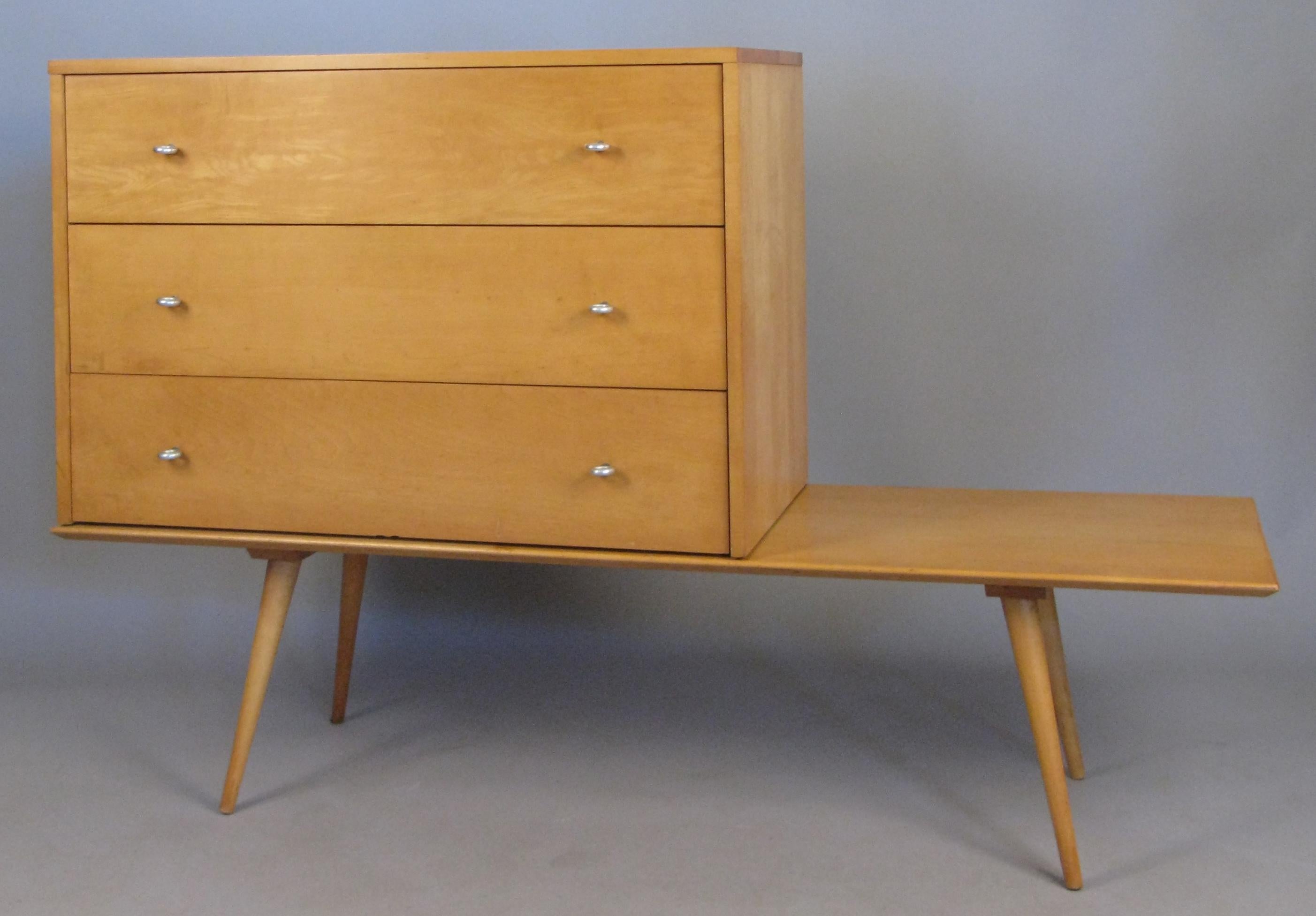 A handsome and Classic 1950s birch three drawer chest with aluminum ring pulls, which rests on a birch bench all designed by Paul McCobb for Winchendon Furniture. In original condition with age expected wear. The left side of the chest has some