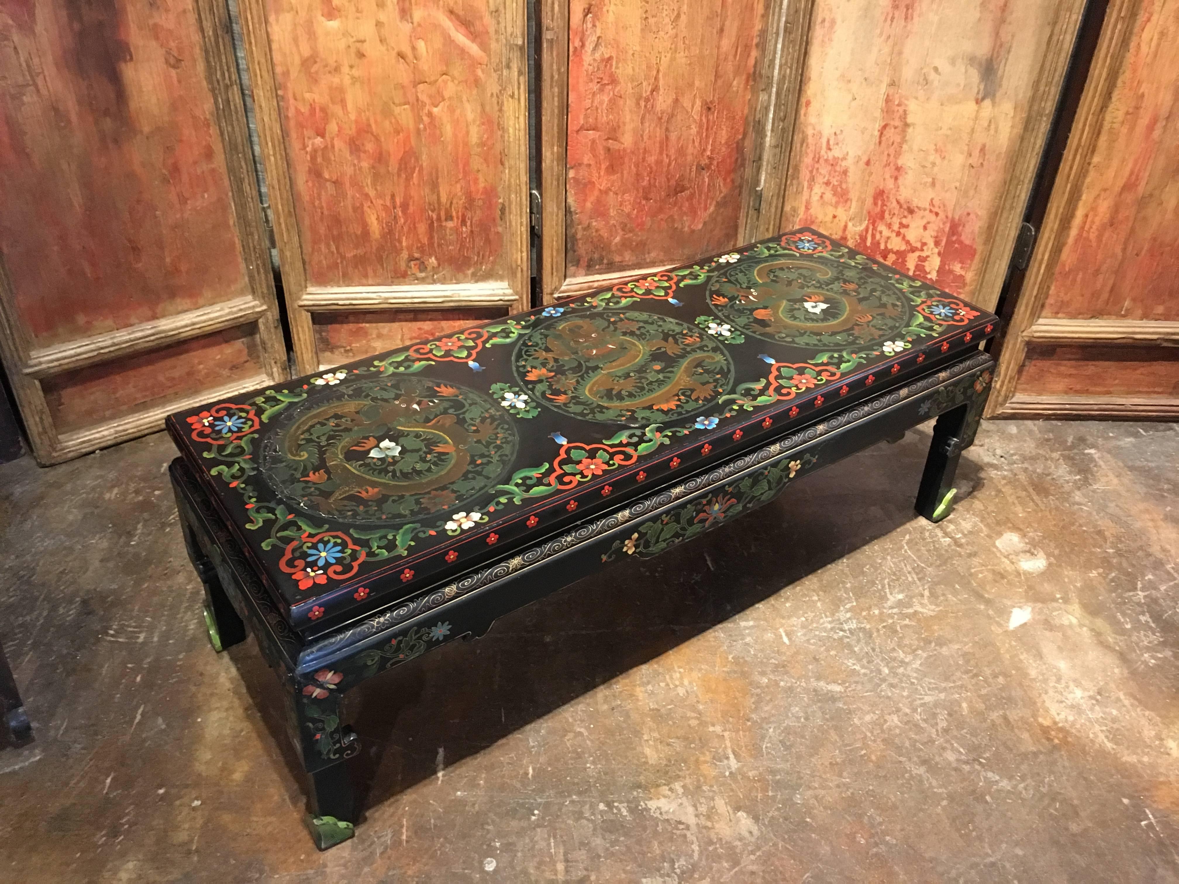 A fun Chinese export Hollywood Regency black lacquer and polychromed coffee table featuring painted roundels of coiled and writhing dragons against a scrolling floral and foliate ground.
Crafted as a traditional Chinese bench, with a narrow waist