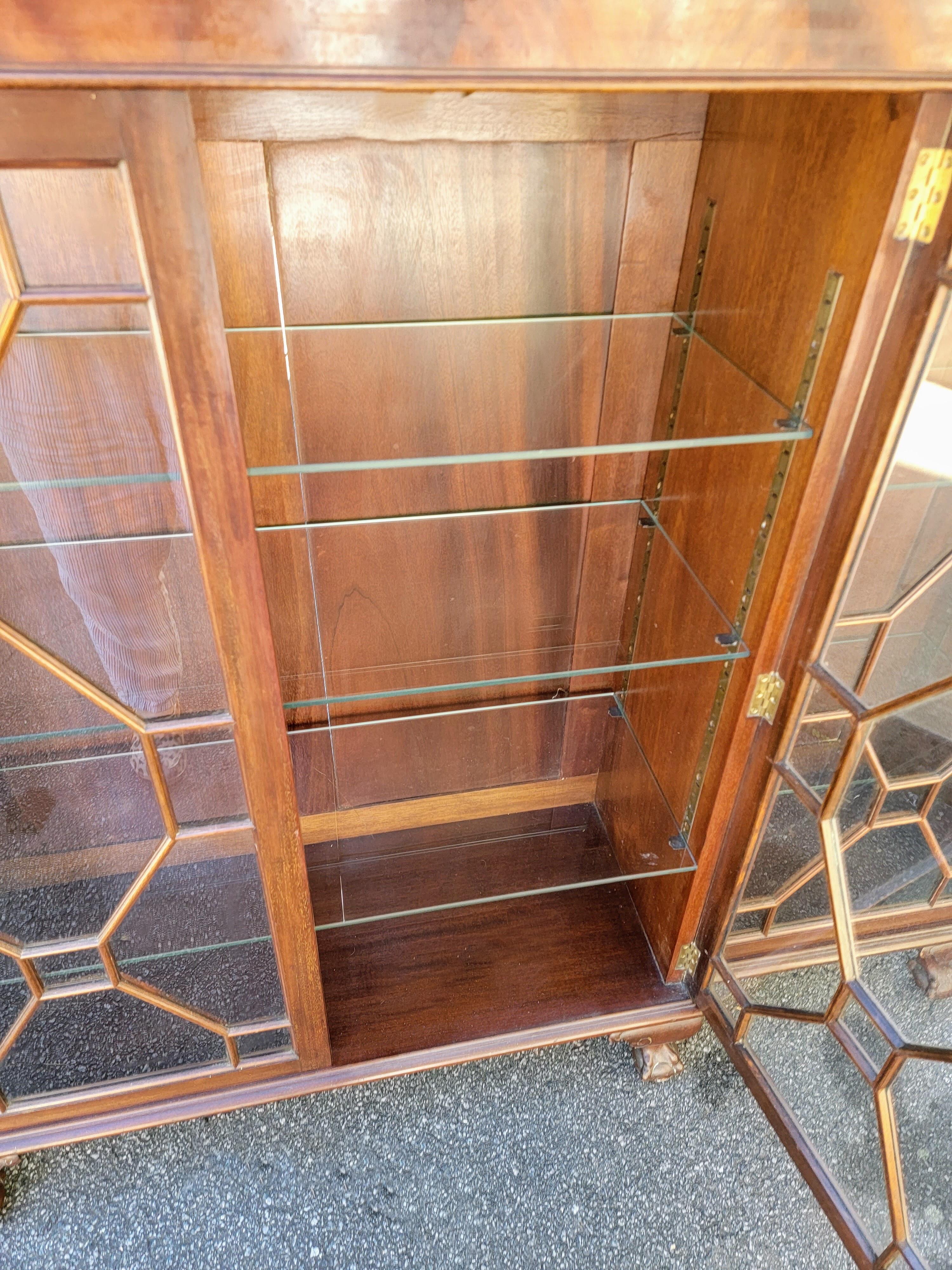 This is a 1950s Chinese chippendale style bookcase or display cabinet. It has ball and claw feet and raised panels on the back. The piece has glass shelving. It is unmarked and in very good condition. Great size!