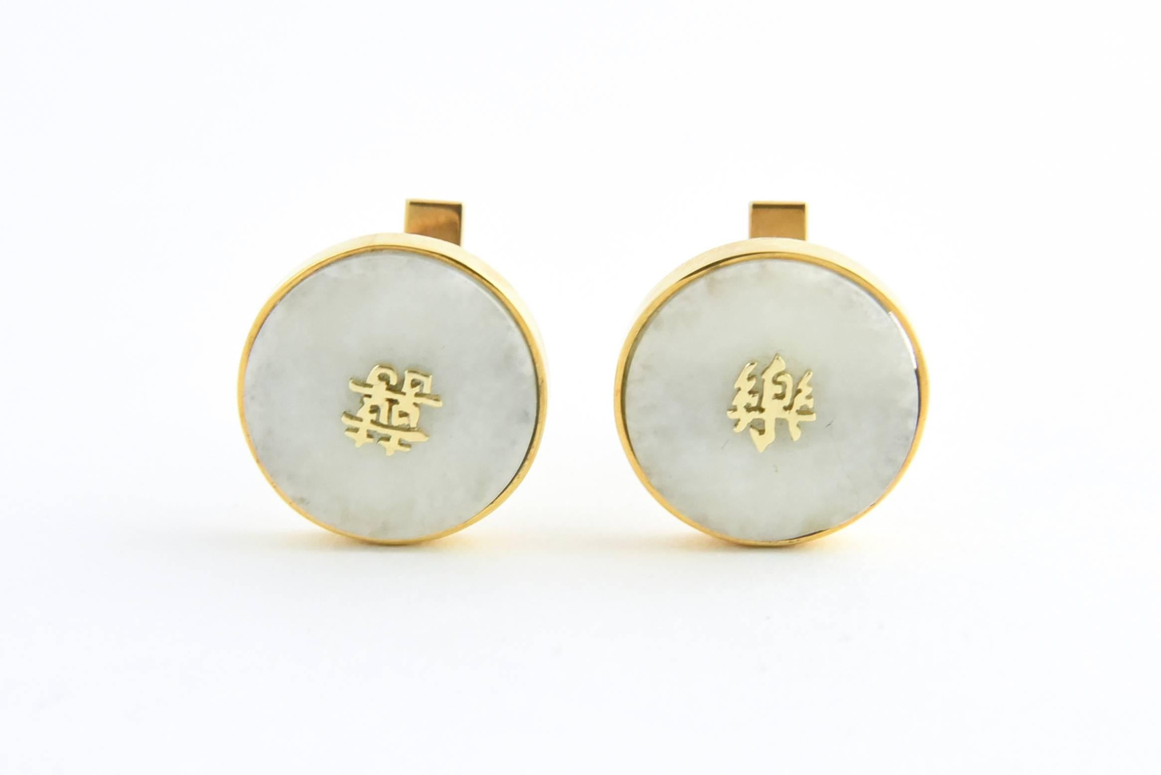 Cuff links featuring jade green disks with 14K yellow gold Chinese characters mounted in a 14K gold bezel.
