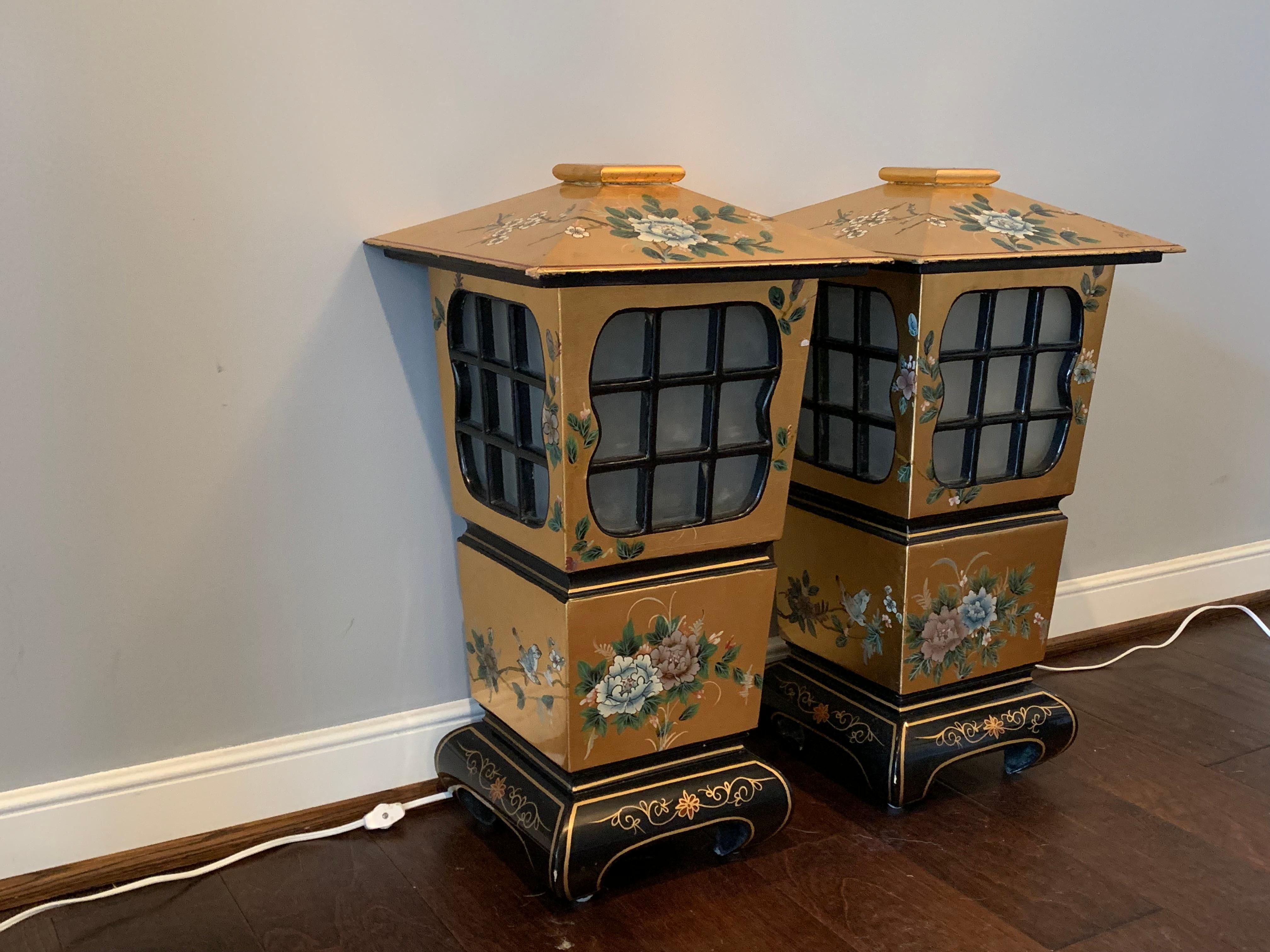 Offered is a gorgeous pair of large, 1950s Asian black and gold lacquered lanterns. Each feature an identical, painted floral and bird motif. Frosted glass windows give a beautiful ambient light. Standard light bulbs. Newly rewired.