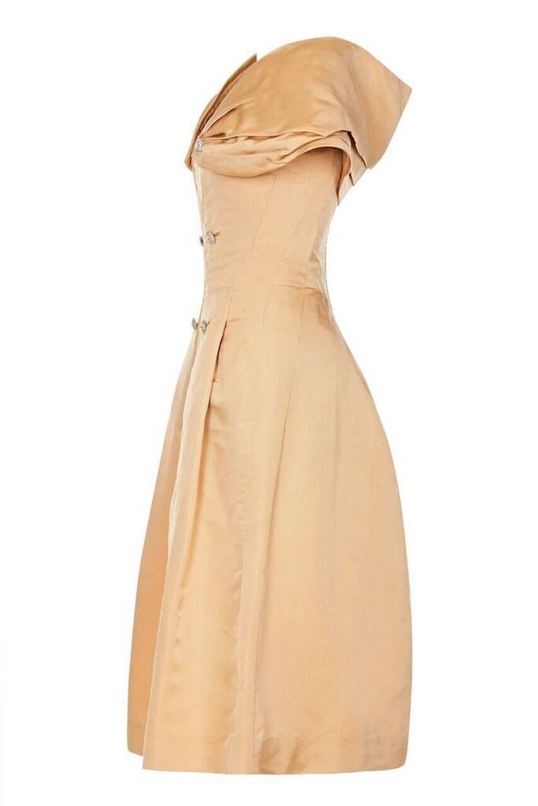 This arresting Christian Dior new York 1950s silk evening dress showcases some incredibly skillful construction and exudes timeless glamour. The fabric is luxurious textured silk in pale gold and has been artfully tailored to create the designer's