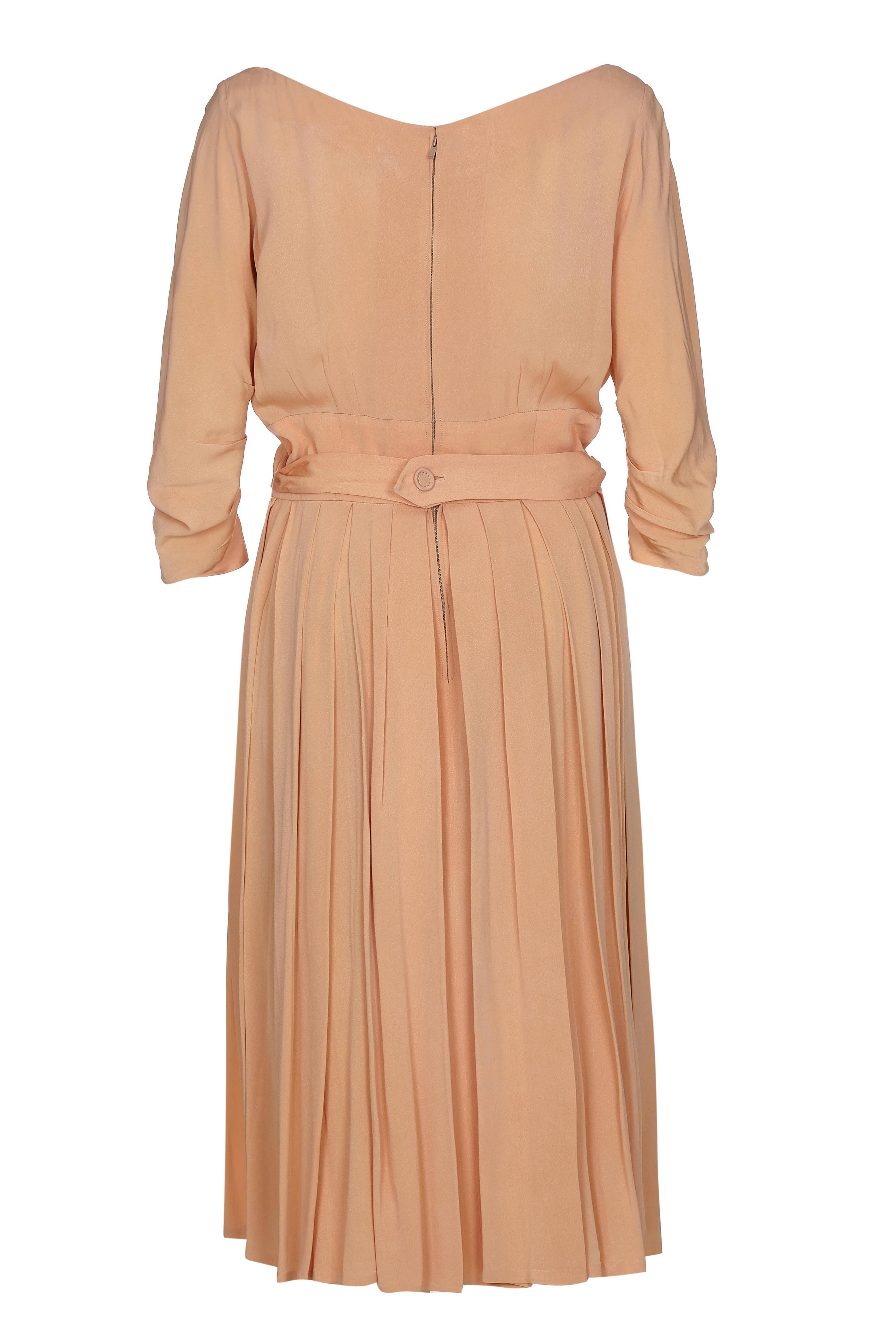 This exceptional 1950s Christian Dior peach silk dress with cross over bodice is a beautiful example of the designer's celebrated and timeless New Look aesthetic. With elegant line and construction, this piece showcases some exquisite tailoring with