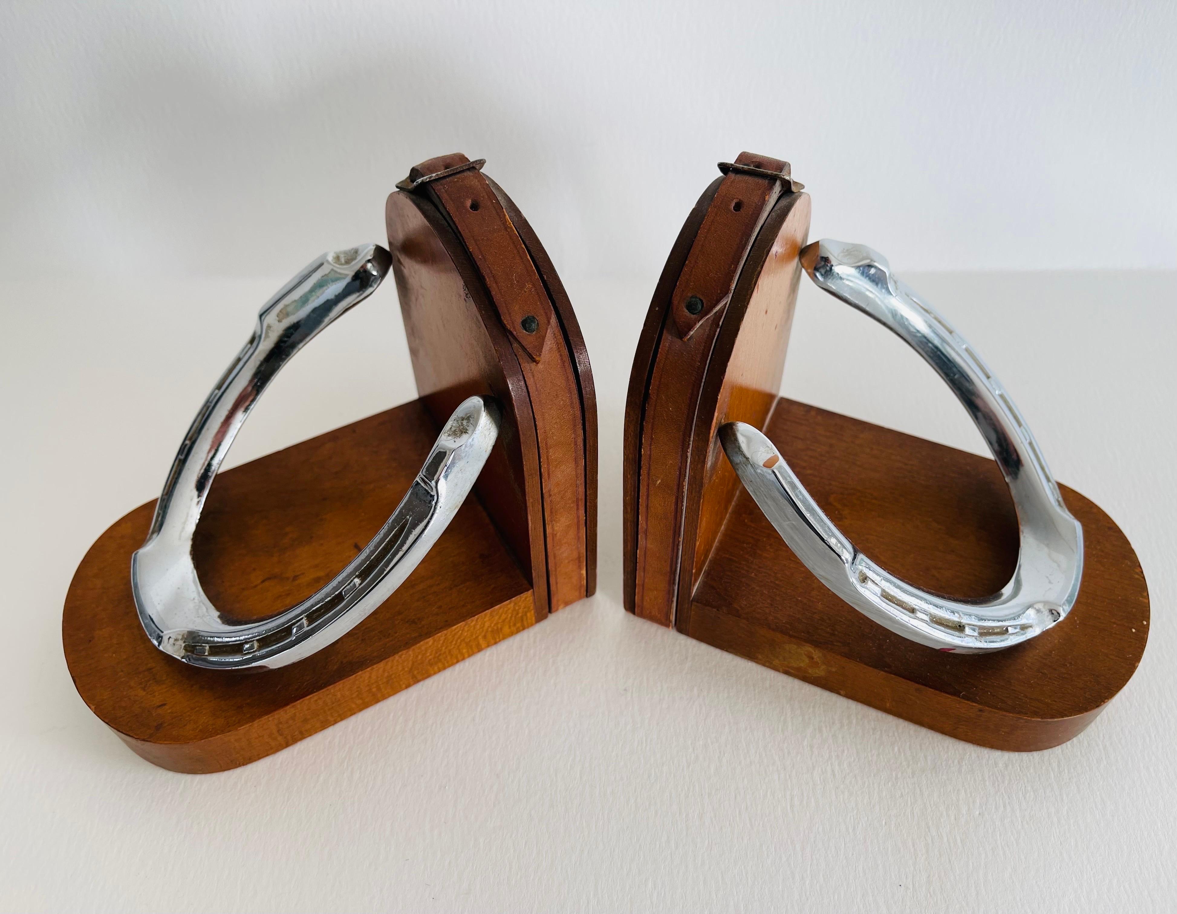 Vintage 1950s pair of bookends with chrome horseshoes and leather straps. Bookends are on a wood base. No marks.