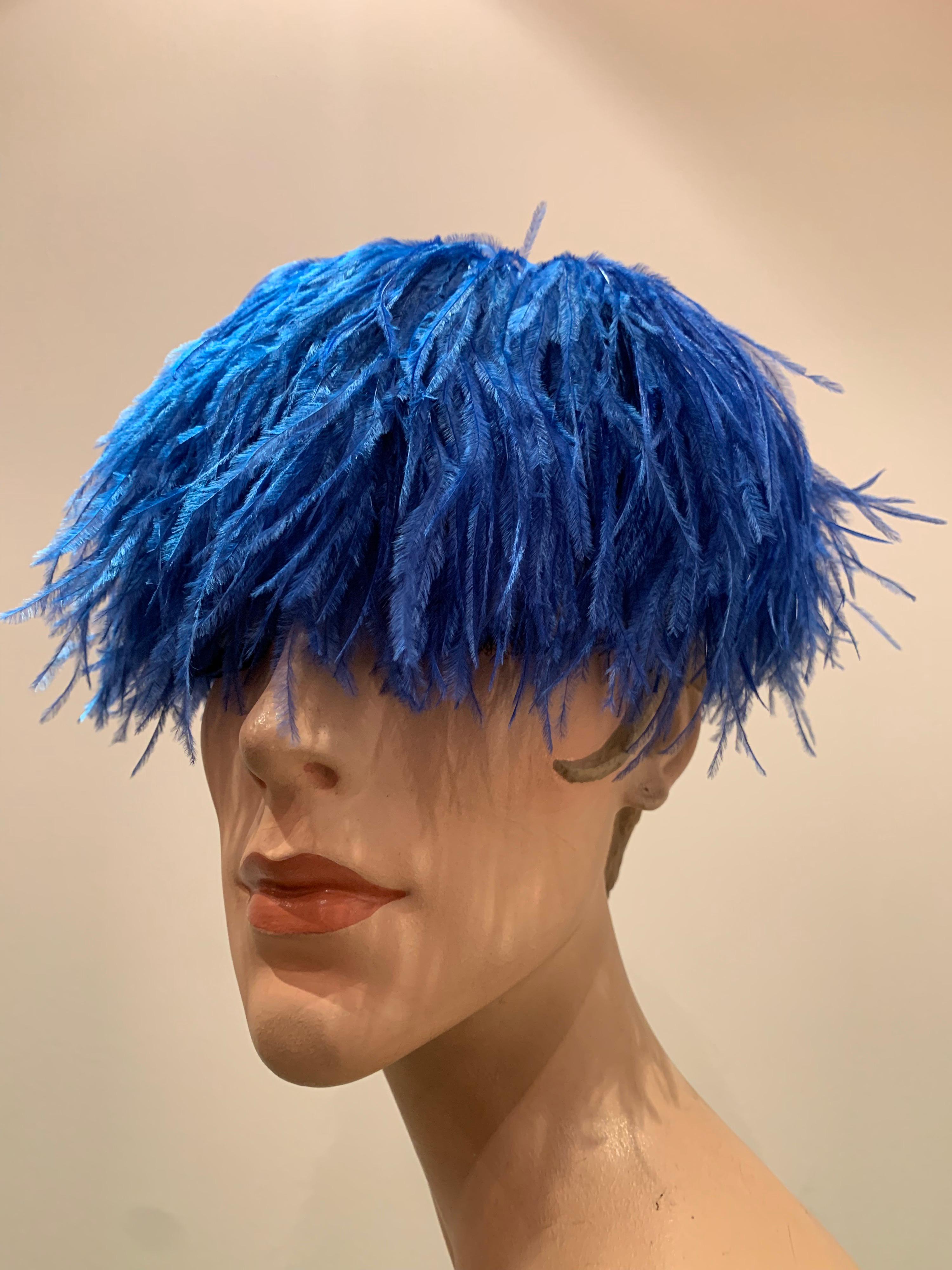 A fabulous 1950s-early 1960s pill box hat from The Woodward Shops covered entirely with lush cobalt blue ostrich feathers with a button-like swirl at center top. Base constructed of stiffened tulle. 