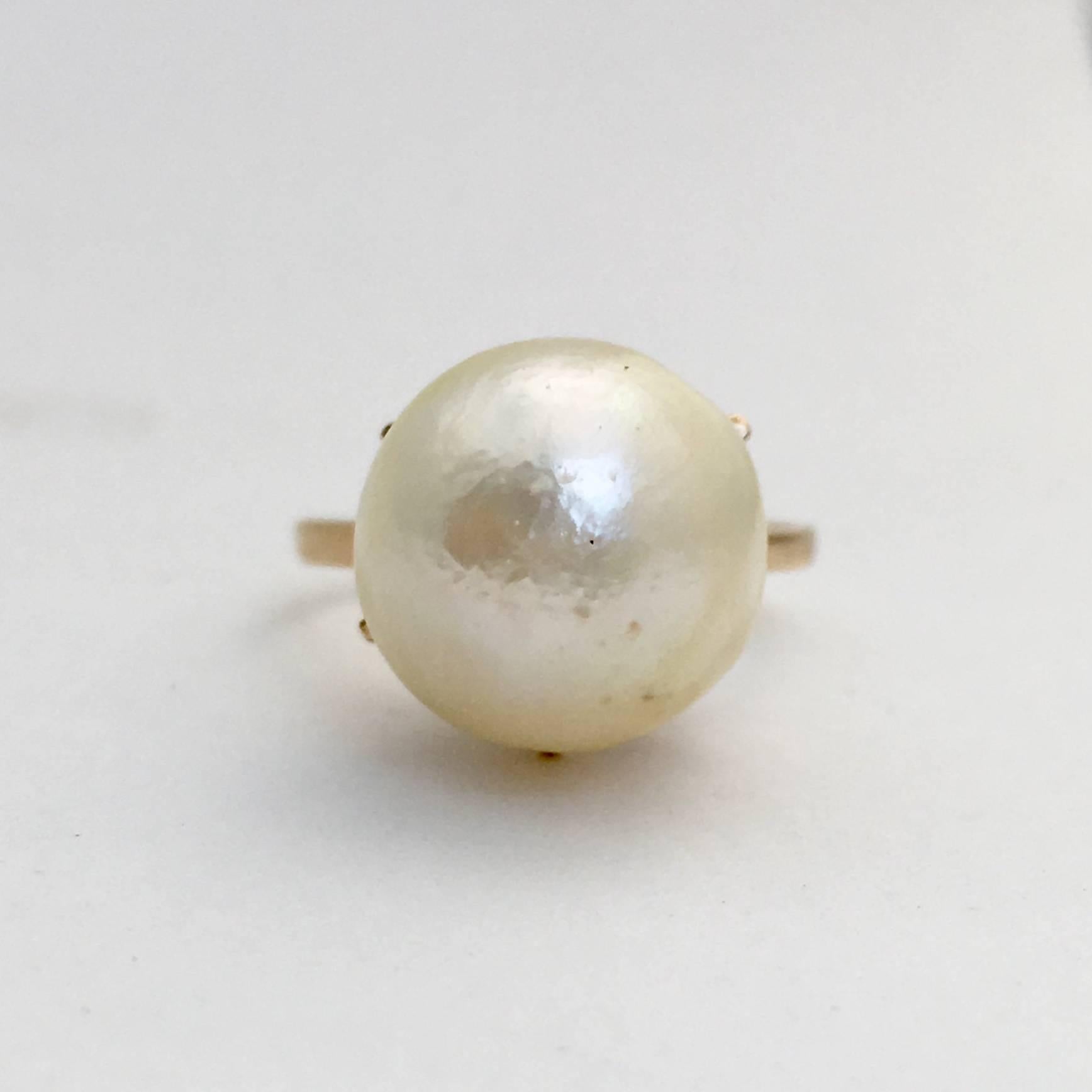 This striking vintage cocktail ring was made in London in 1959. The sizeable baroque pearl measures 1.2cm by 1.2cm and nestles in its 9ct yellow gold pronged setting. The pearl has long been a staple in jewellery elegance, favoured by style icons