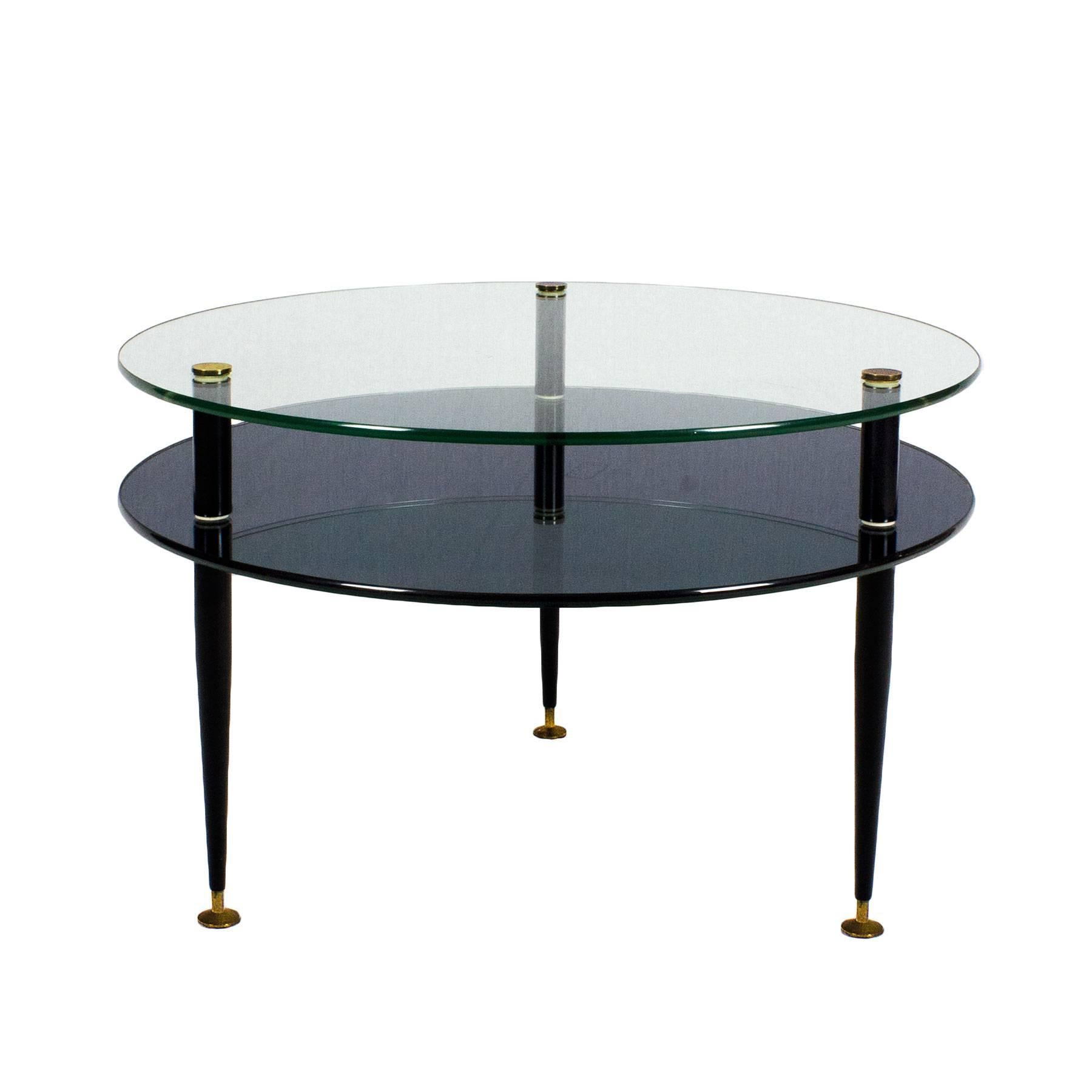 High quality coffee table, black lacquered steel feet with adjusting screws and solid brass decorating heads. Glass on top and blue mirror at the bottom,

Italy, circa 1950.