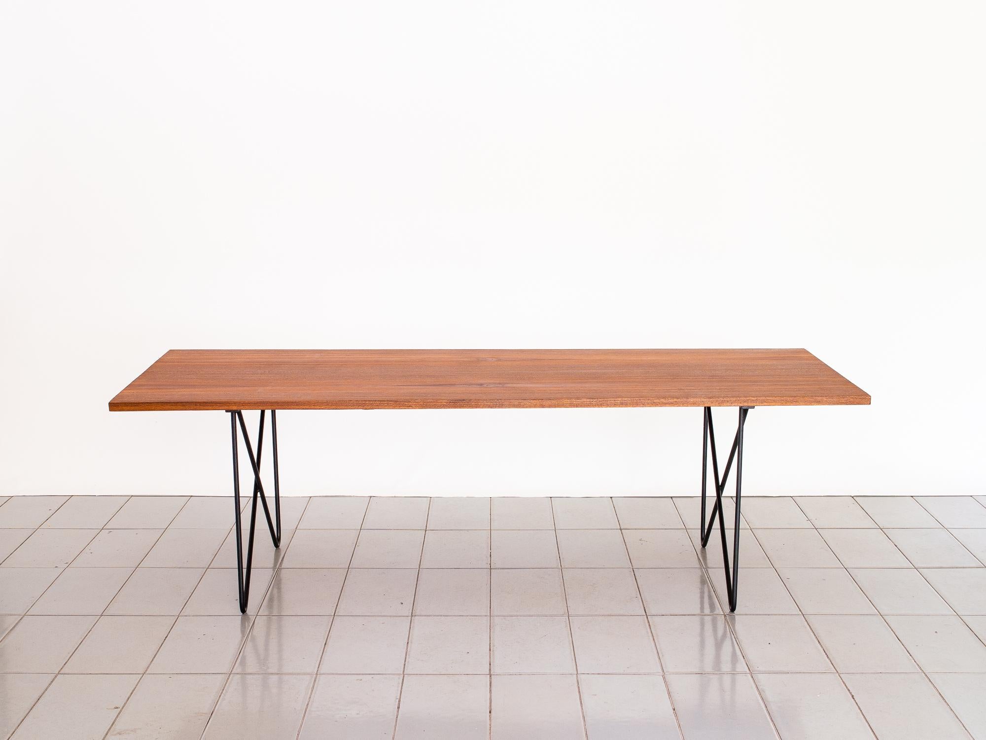 This great and lightweight piece is fully veneered in Asian teak, and have beautiful crossing legs as base. The attribution to Ernesto Hauner comes from the design of the legs, very usual of his super brief independent production before opening his