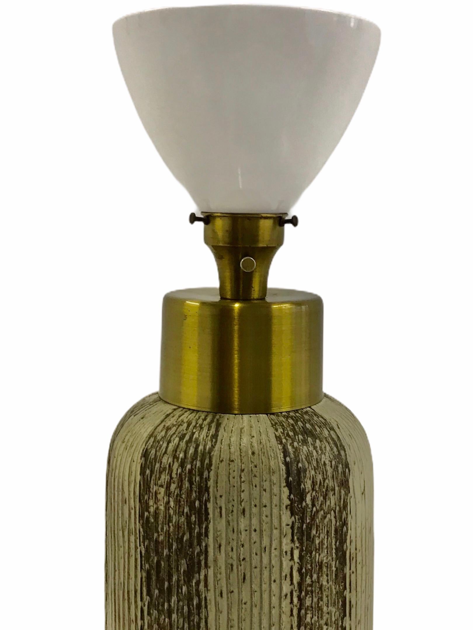 Exhibiting a textural pottery form in brown and grey tones in the style of Claude Conover, this table Lamp with brass mounts and a milk glass diffuser is a 1950s delight. Sophisticated and elegant, it is masculine and modern. With all original