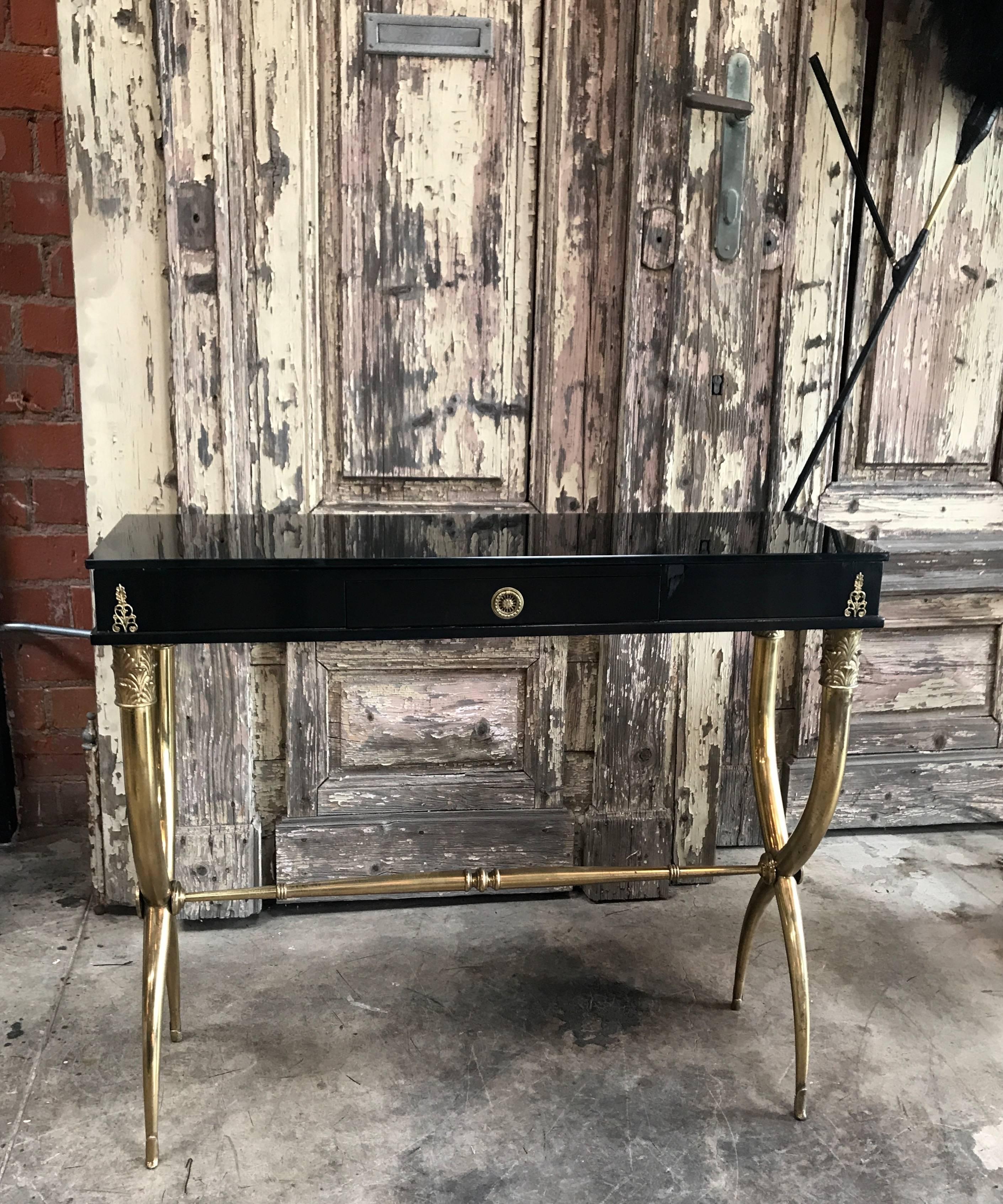 A midcentury Italian console table with black finish and dark black mirrored glass top.
Elegant clean lines with unique curved and intertwined brass legs.