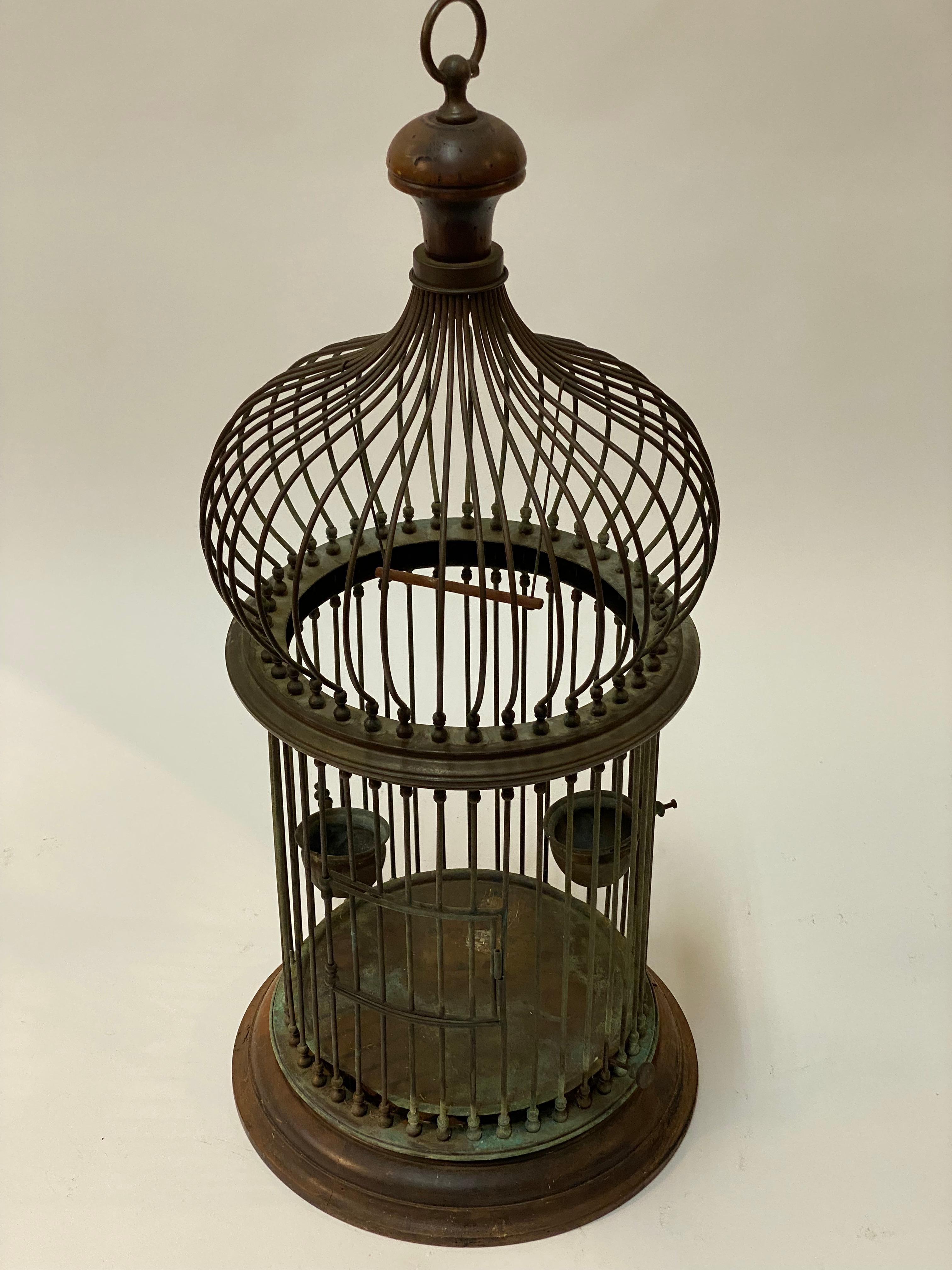 A very well made and constructed tubular copper rods and fruitwood onion dome Italian birdcage. Signed with a metal tag on the loop hanger, Italy. The cage includes a swing, two adjustable height cups for feed and water, an adjustable floor pan and