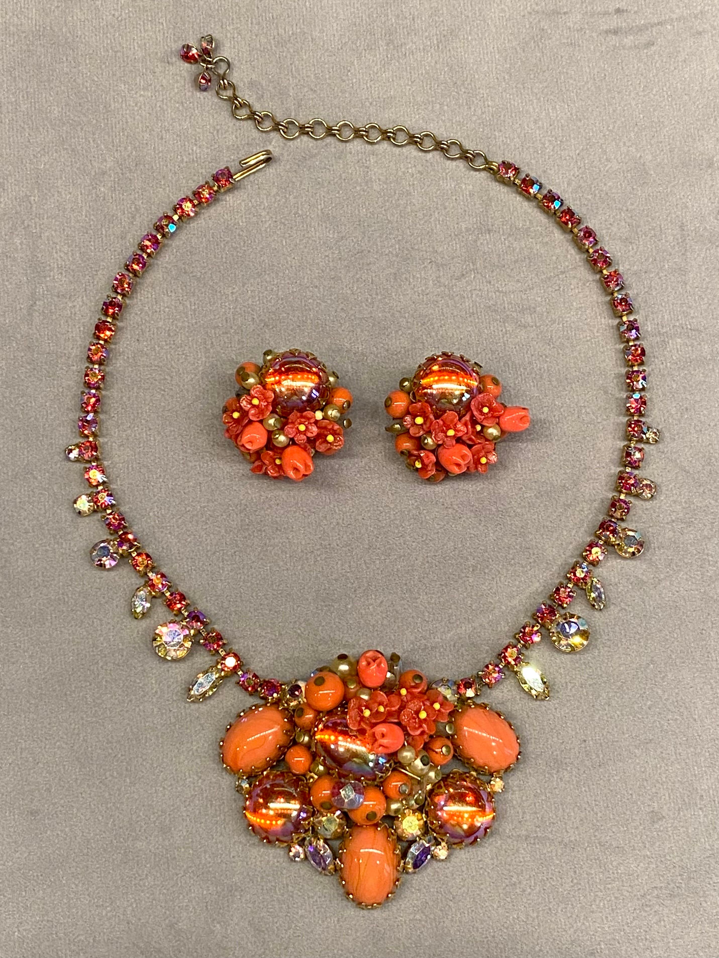 This beautiful unsigned 1950s jewelry set is truly eye catching and unique. It features beautiful coral glass and dragon breath cabochons in the 2.5 inch wide and 2 inch tall central cluster. Additionally, there are handcrafted coral glass flowers,