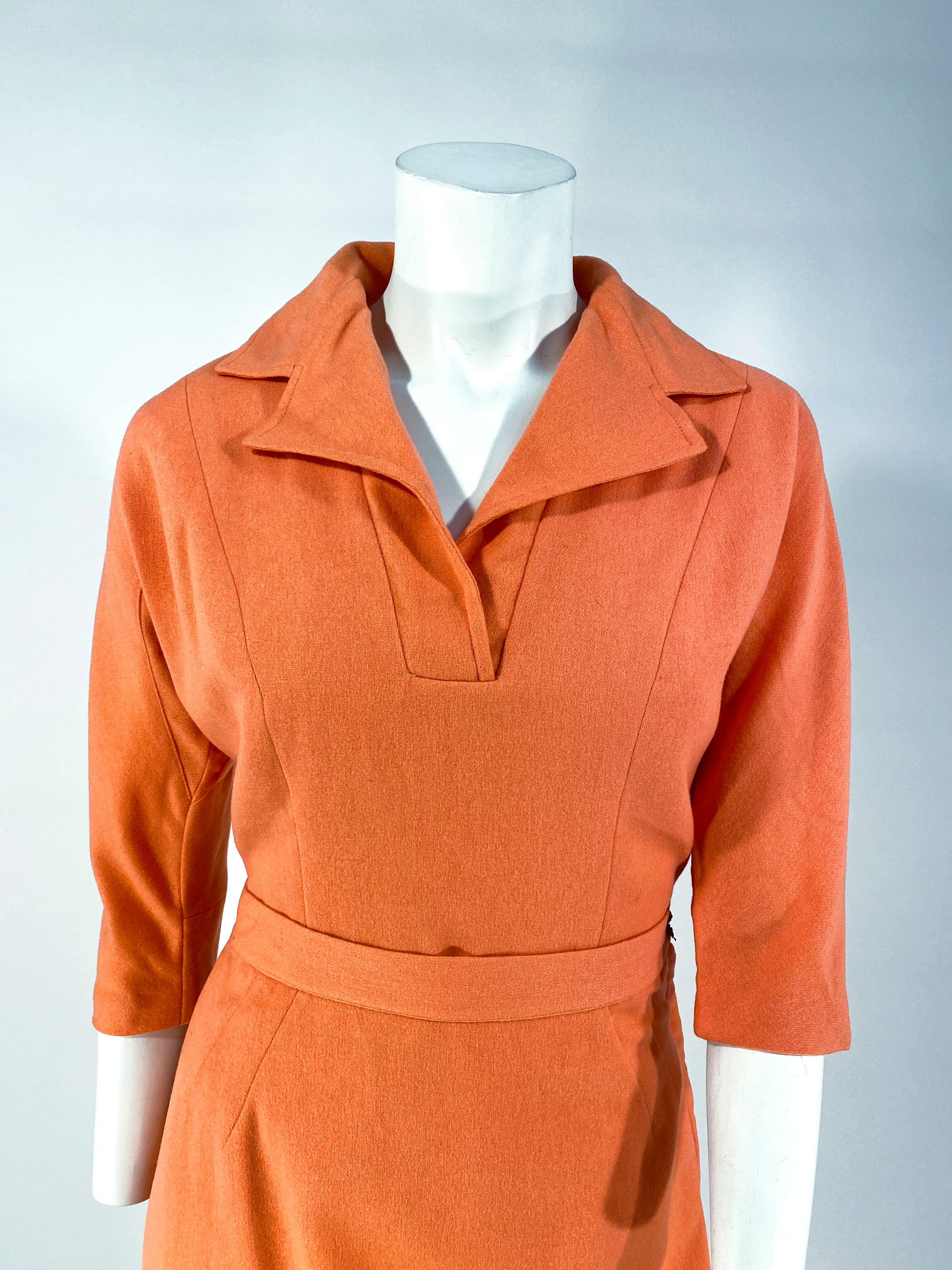 1950s coral colored light wool blouse and skirt set. This Day suit is fully lined with three-fourths length tapered sleeves with underarm gusset, a lapeled collar, and a metal side zipper closure. The pencil skirt is knee-length with a metal side