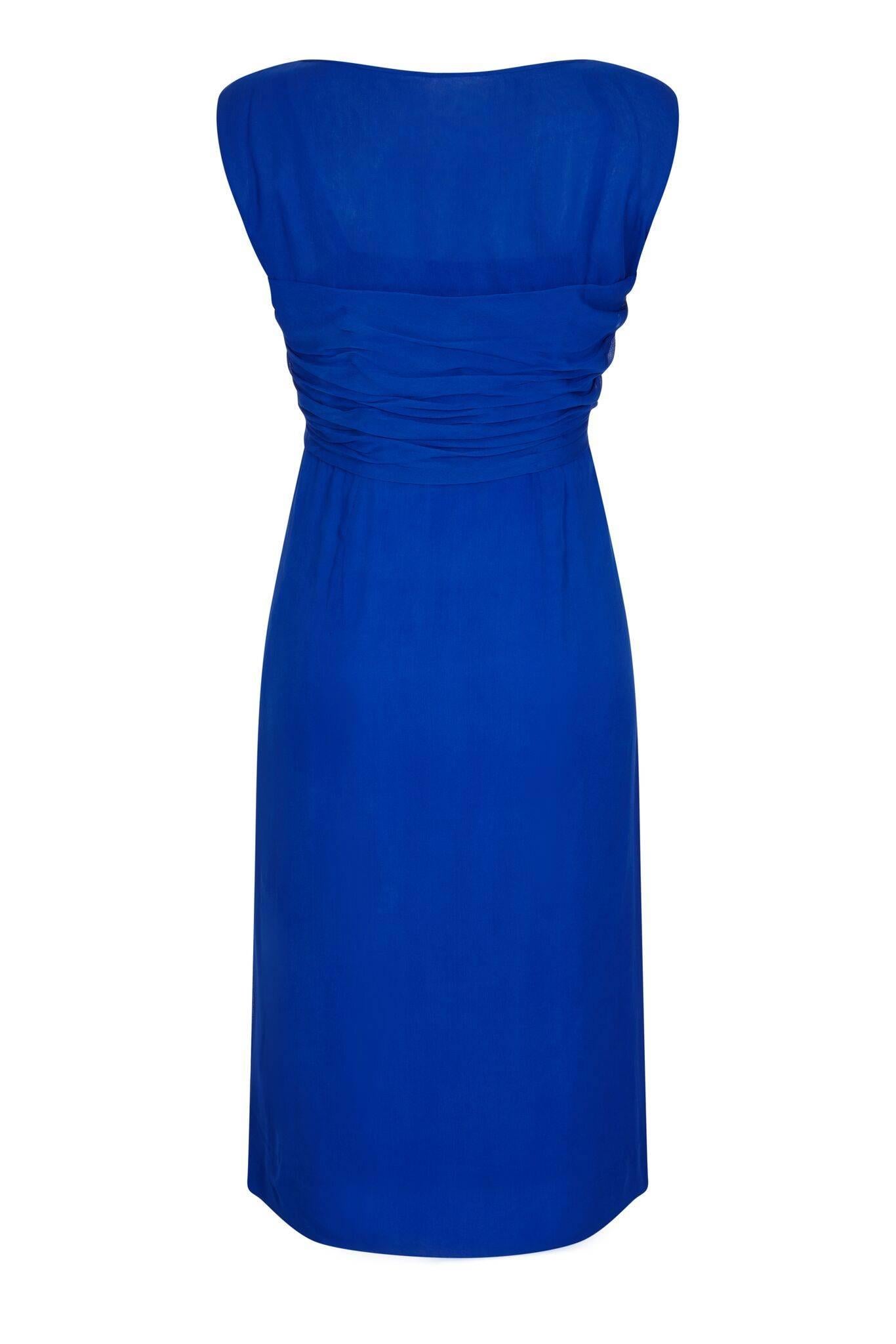Cette charmante robe du soir en mousseline de soie des années 1950, de couleur bleu cobalt, a été magnifiquement confectionnée selon les normes de la haute couture et se trouve dans un état vintage impeccable. La superposition de mousseline de soie