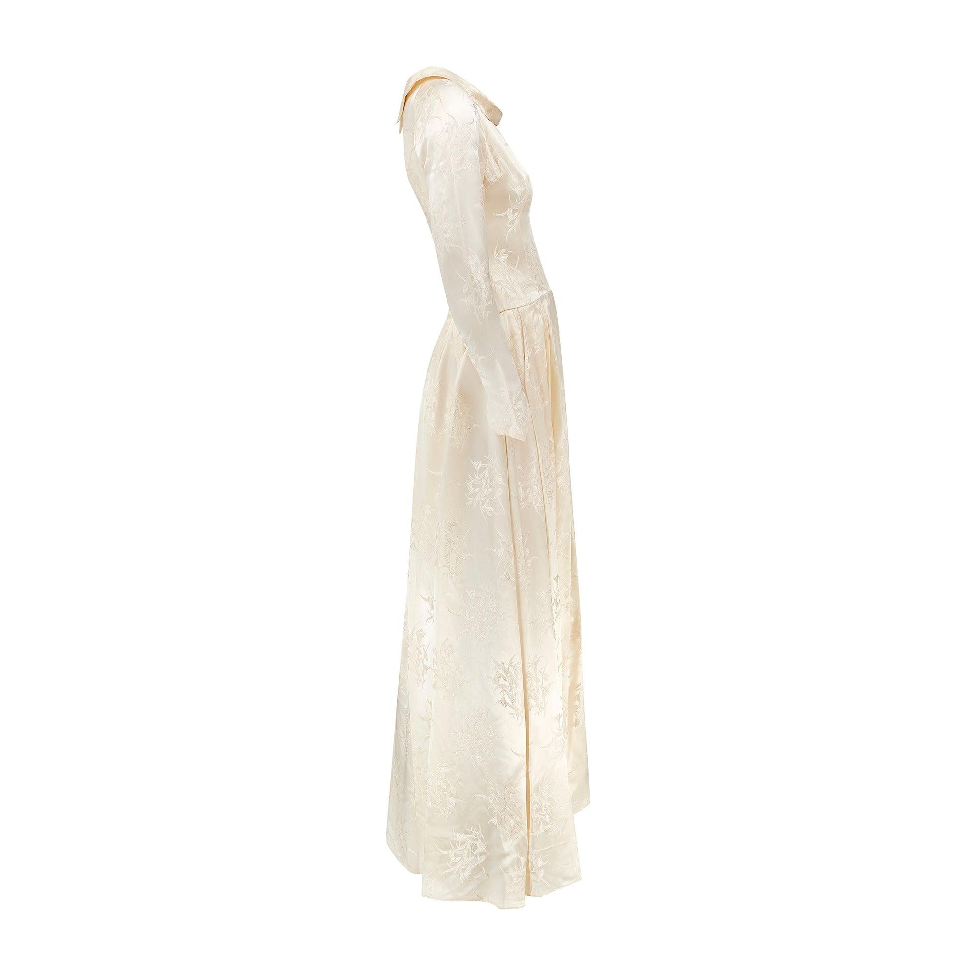 Este auténtico vestido de novia vintage de los años 50 está confeccionado en un detallado jacquard de un rico tono crema blanquecino.  Adaptada a una silueta clásica de los años 50, con cintura ceñida y falda con vuelo que se arremolina en torno a