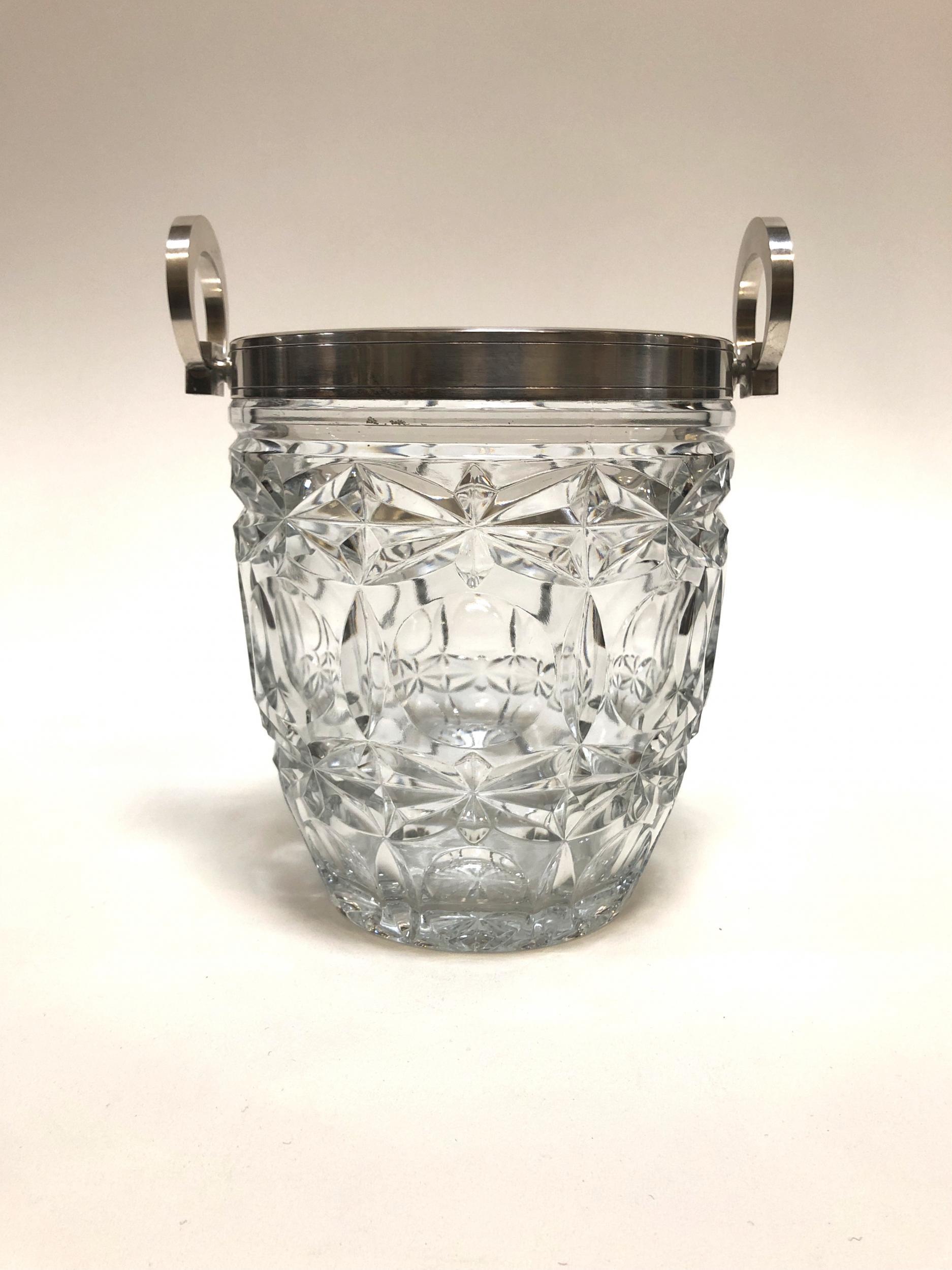 This is an intricately carved mid century crystal ice bucket with silver trim and handles that originated in France in the 1950s and was manufactured by E.L. as shown etched on the handle. 

Champagne never looked so glamourous in this beautiful
