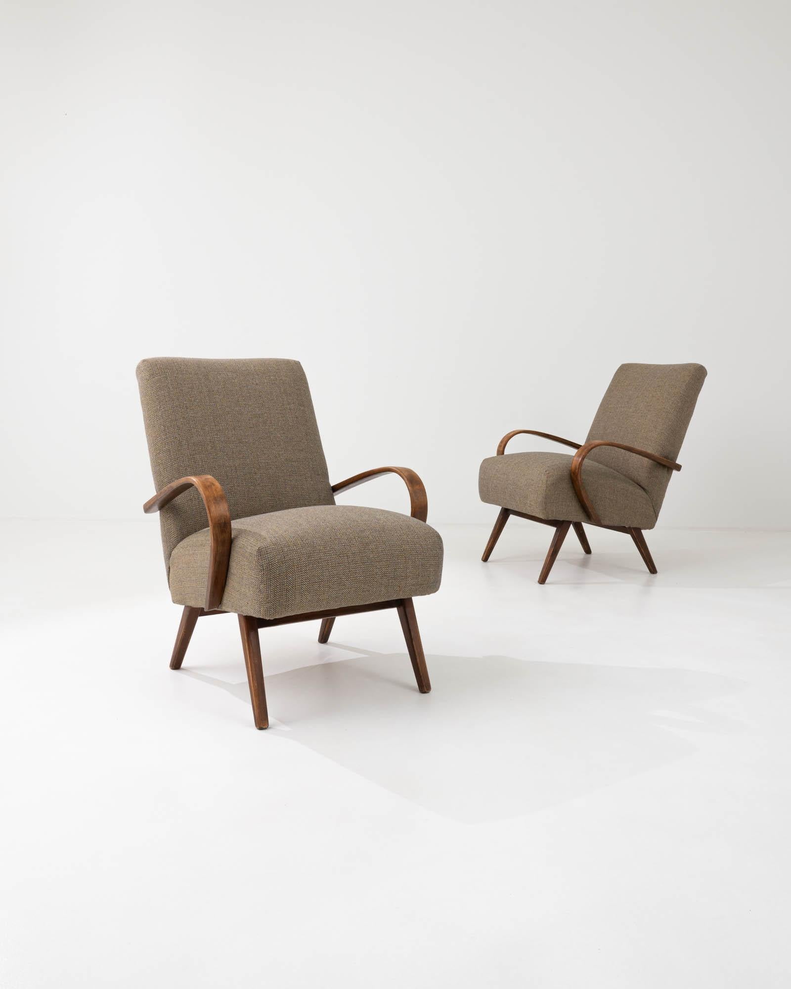 Produced in the former Czechoslovakia, this pair of bentwood armchairs from circa 1950 are re-upholstered with an updated neutral fabric. The cotton-linen blend was chosen to compliment the vintage elegance of the black hardwood frame. Comfortable