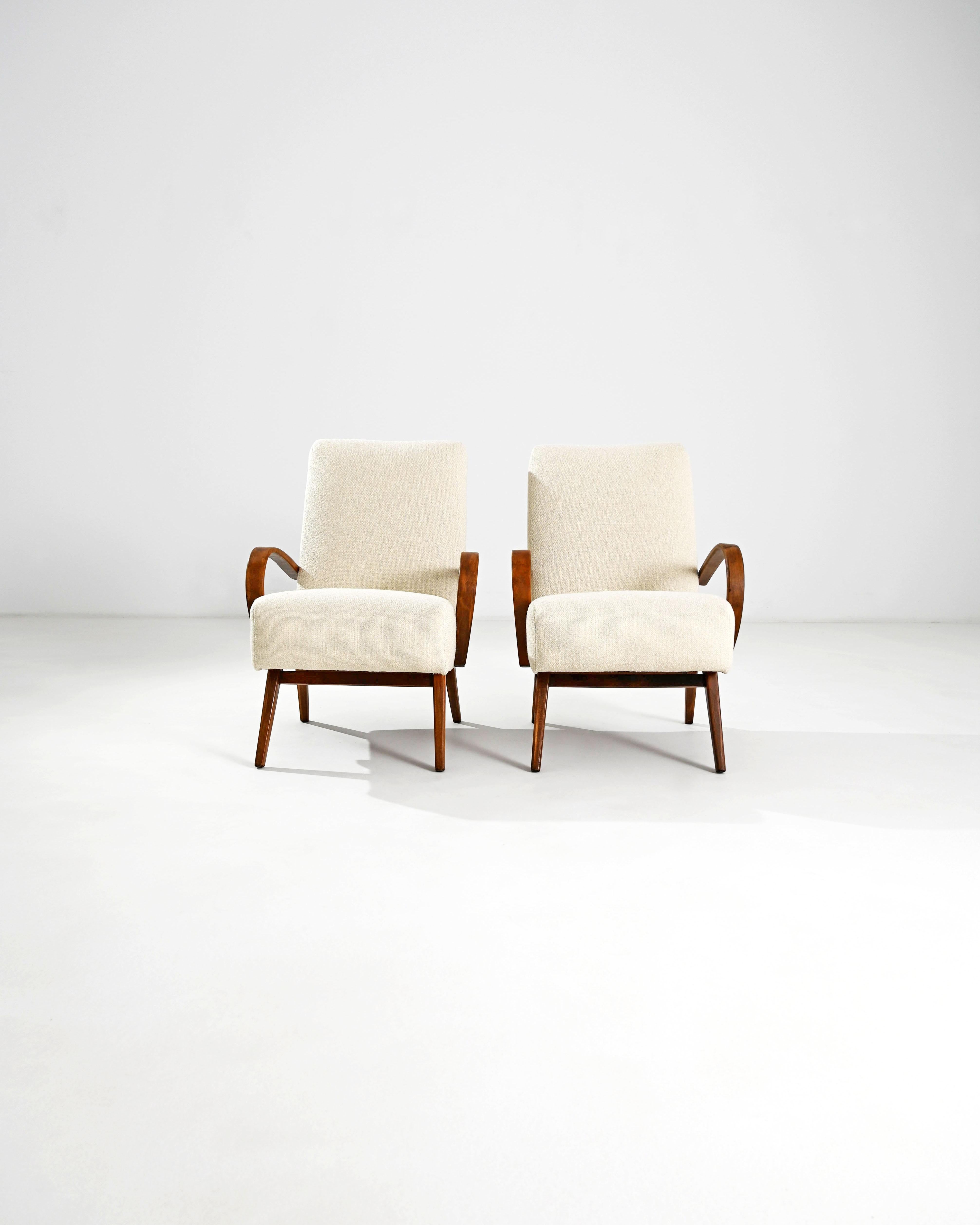 Produced in the former Czechoslovakia, this pair of bentwood armchairs from circa 1950 are re-upholstered with an updated cream boucle fabric. The cotton-linen blend was chosen to compliment the vintage elegance of the polished hardwood frame.