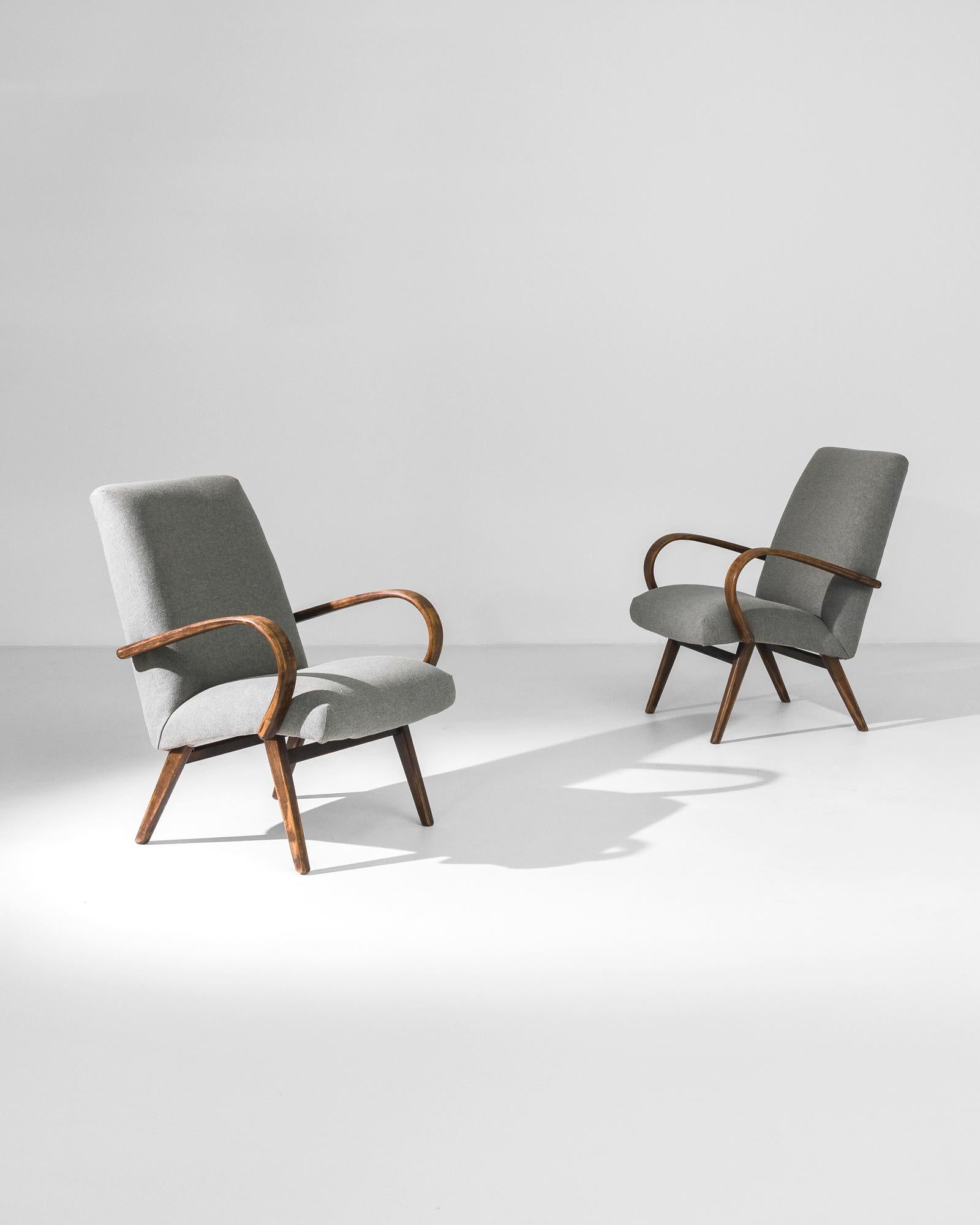 Fabriquée dans l'ancienne Tchécoslovaquie, cette paire de fauteuils en bois courbé datant d'environ 1950 a été retapissée avec un tissu gris moderne. Le mélange de coton et de lin a été choisi pour compléter l'élégance vintage du cadre en bois dur
