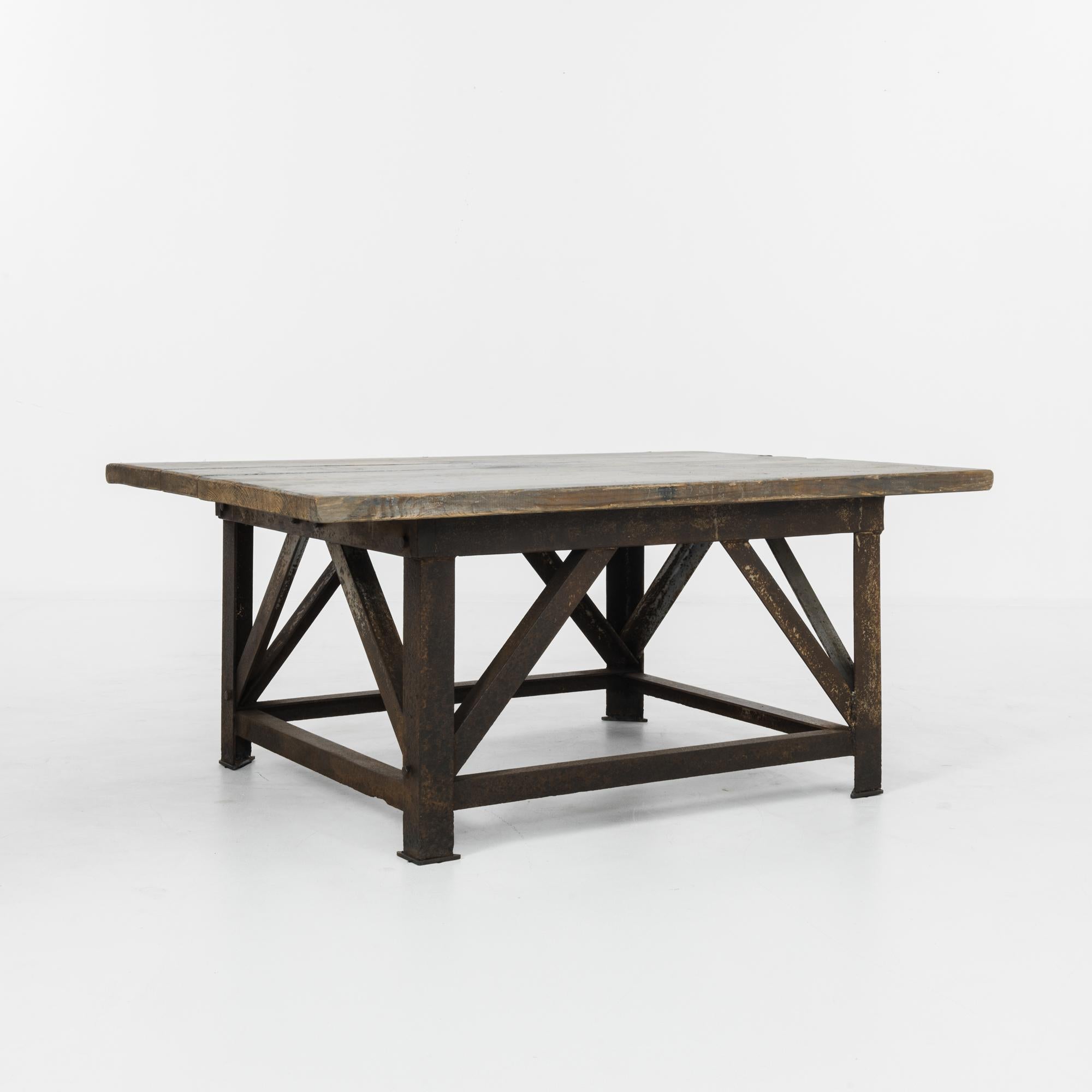 A table from 1950s Czechia with an industrial aesthetic. A rectangular tabletop of wooden boards rests atop an iron base; the reddish, oxidized hue of the metal and the natural finish of the wood make for a pleasing contrast of materials. The
