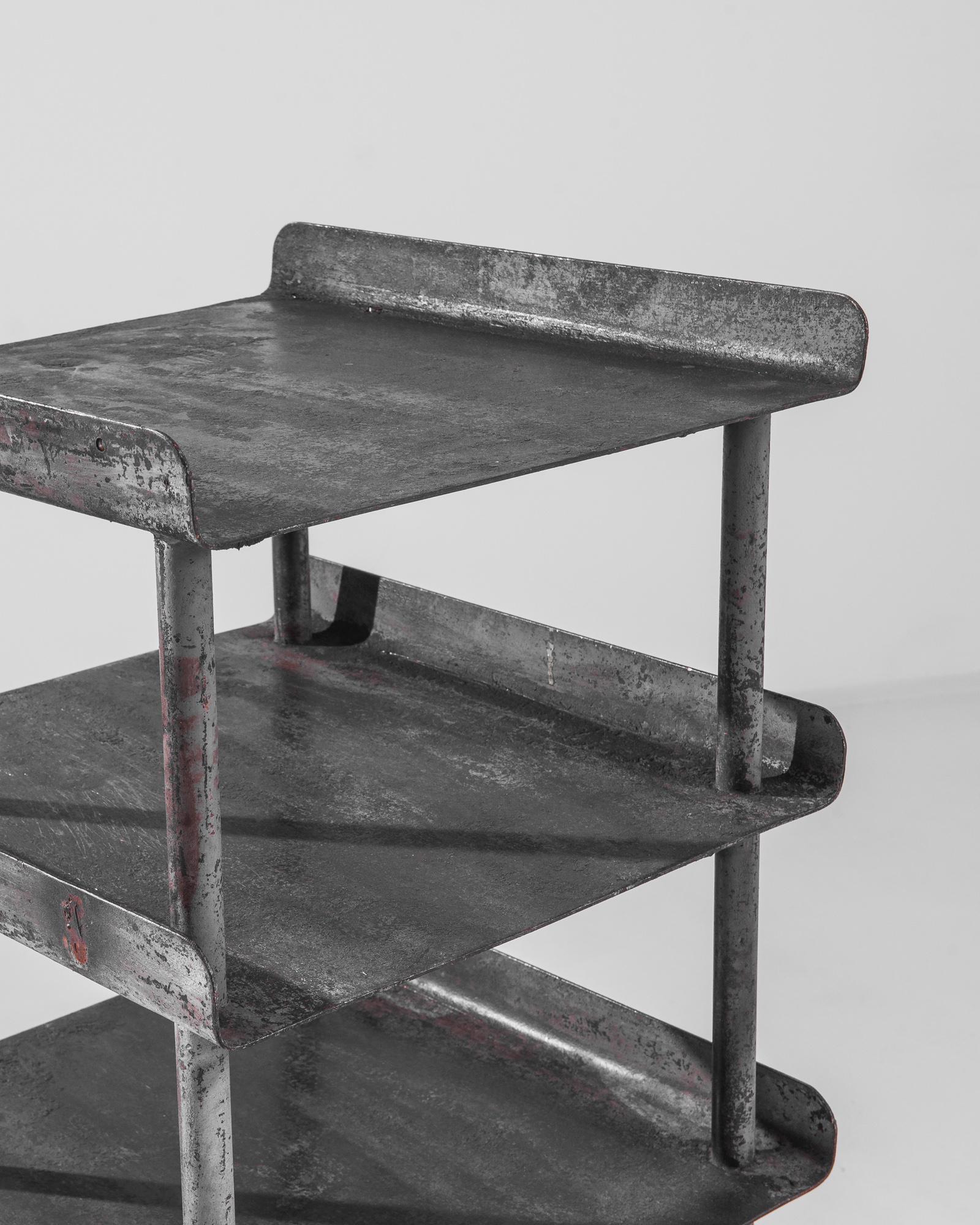 Ein Metallregal aus Tschechien, hergestellt um 1950. Dieses kurze Regal mit einer Höhe von etwa zwei Metern besteht aus drei Reihen geflügelter Böden, die durch dünne zylindrische Stützen voneinander getrennt sind und auf runden Füßen mit kurzen