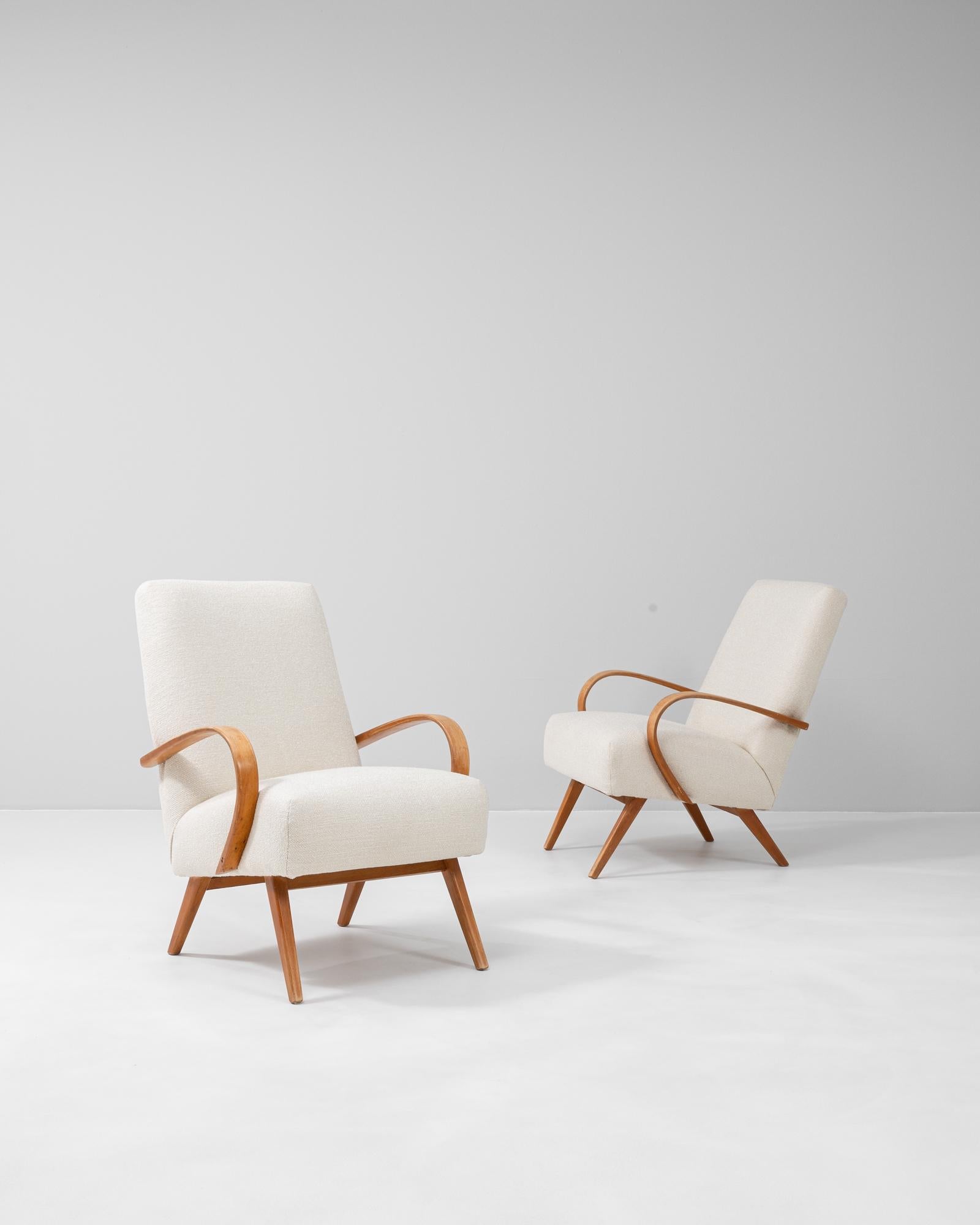 This pair of upholstered armchairs by Jindřich Halabala, dating to the 1950s, is a striking example of mid-century Czech design. Known for his innovative approach to form and comfort, Halabala designed these chairs with gently curved armrests