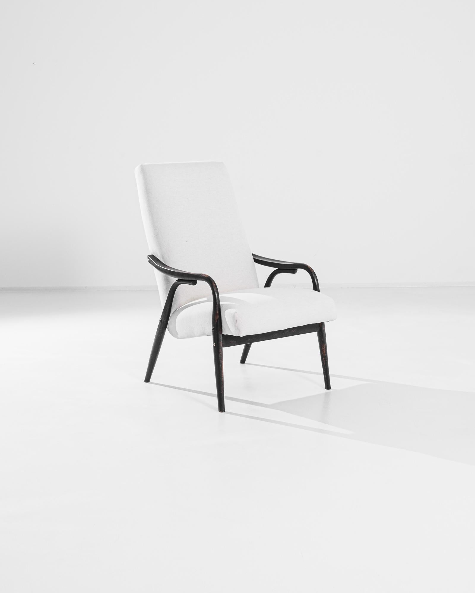 Introduisez une élégance intemporelle dans votre espace de vie avec ce superbe fauteuil tapissé tchèque des années 1950. Cette pièce vintage associe un cadre en bois noir élégant à un revêtement doux de couleur crème, créant ainsi un look