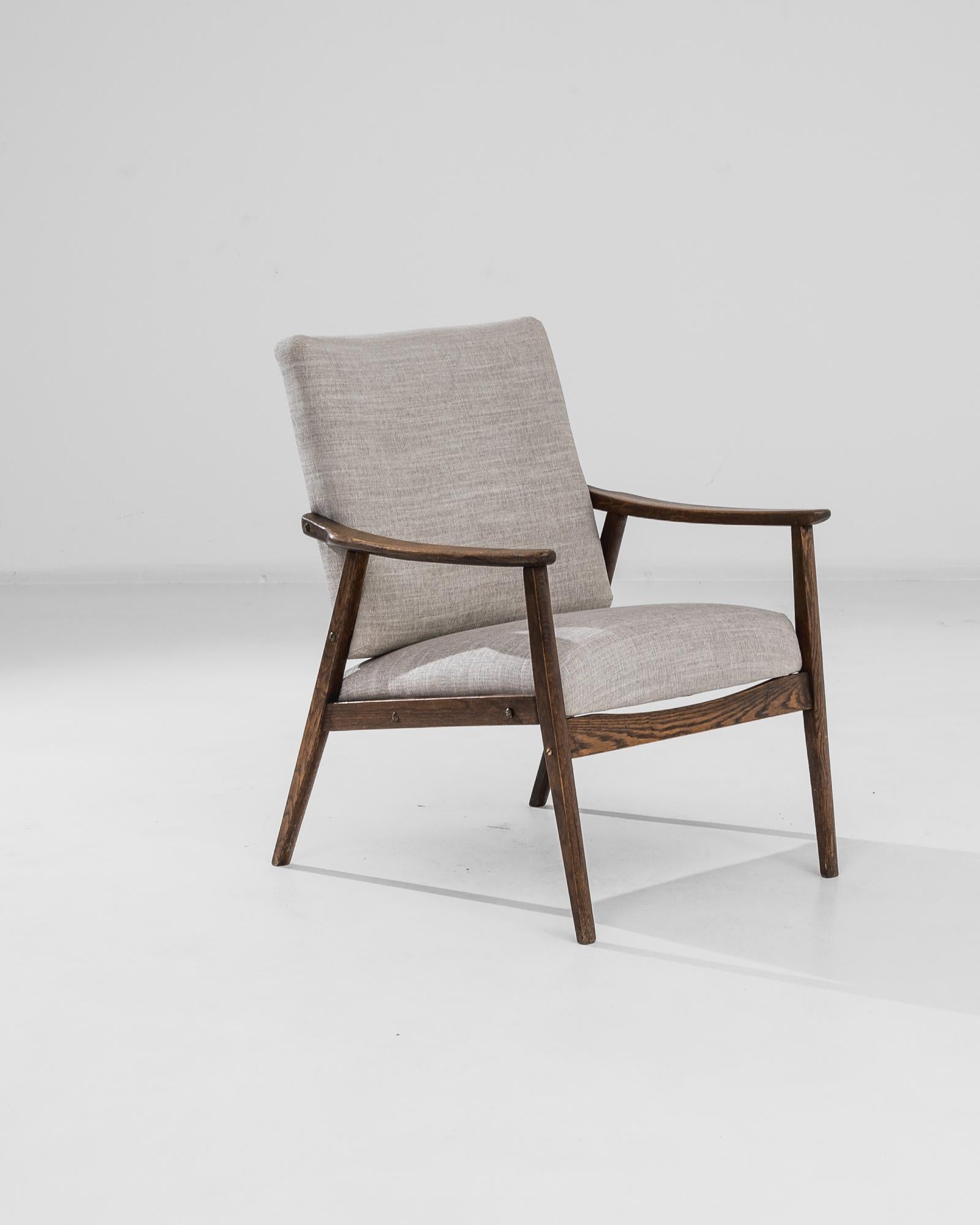 Infuse your home with mid-century charm with this exquisite 1950s Czech Upholstered Armchair. This elegant piece features a sleek wooden frame with beautifully angled armrests, highlighting the craftsmanship of the era. The soft, neutral-toned