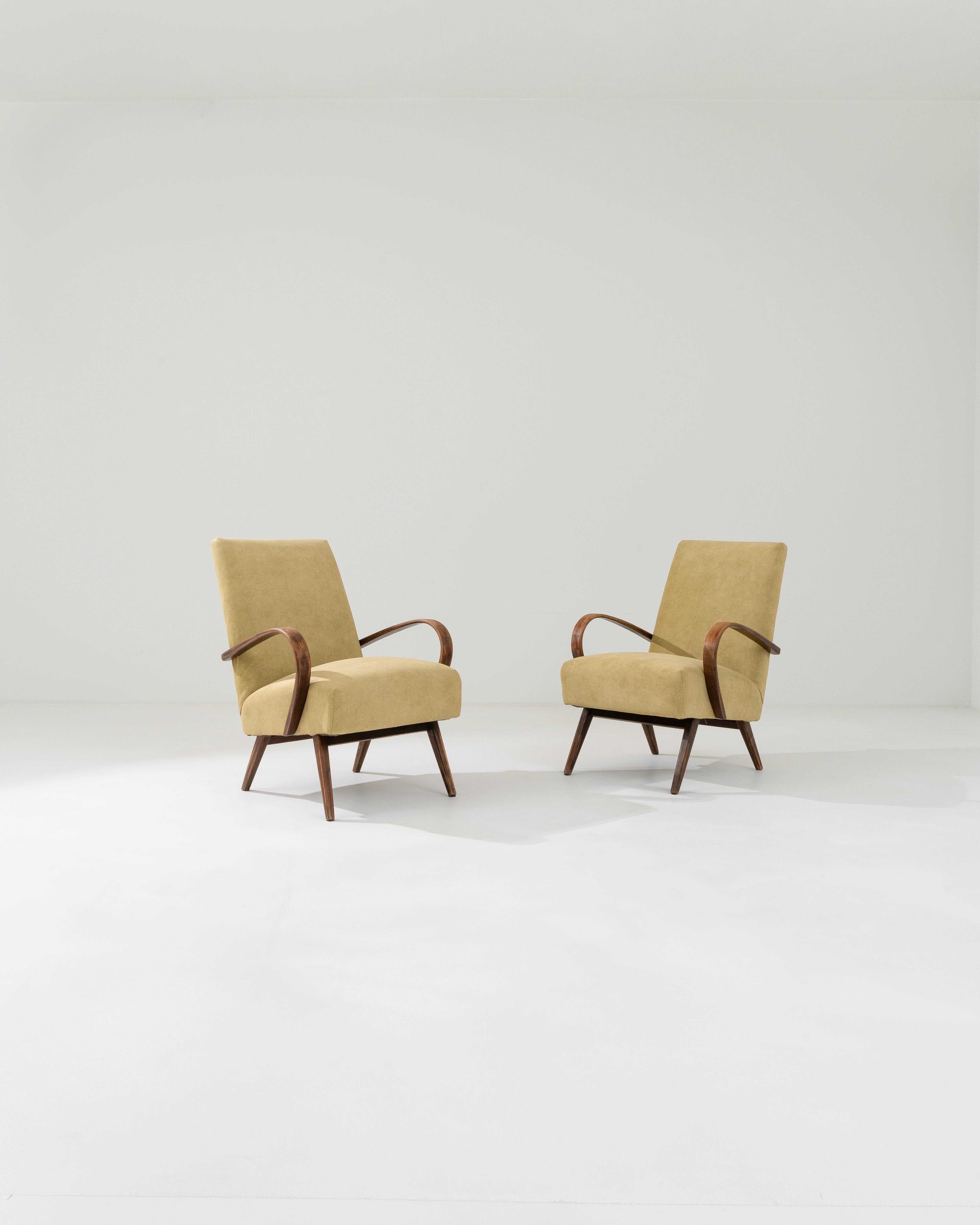Produced in the former Czechoslovakia, this pair of bentwood armchairs from circa 1950 are re-upholstered with an updated ochre fabric. The upholstery was chosen to compliment the vintage elegance of the hardwood frame. Warm yellow combines with the