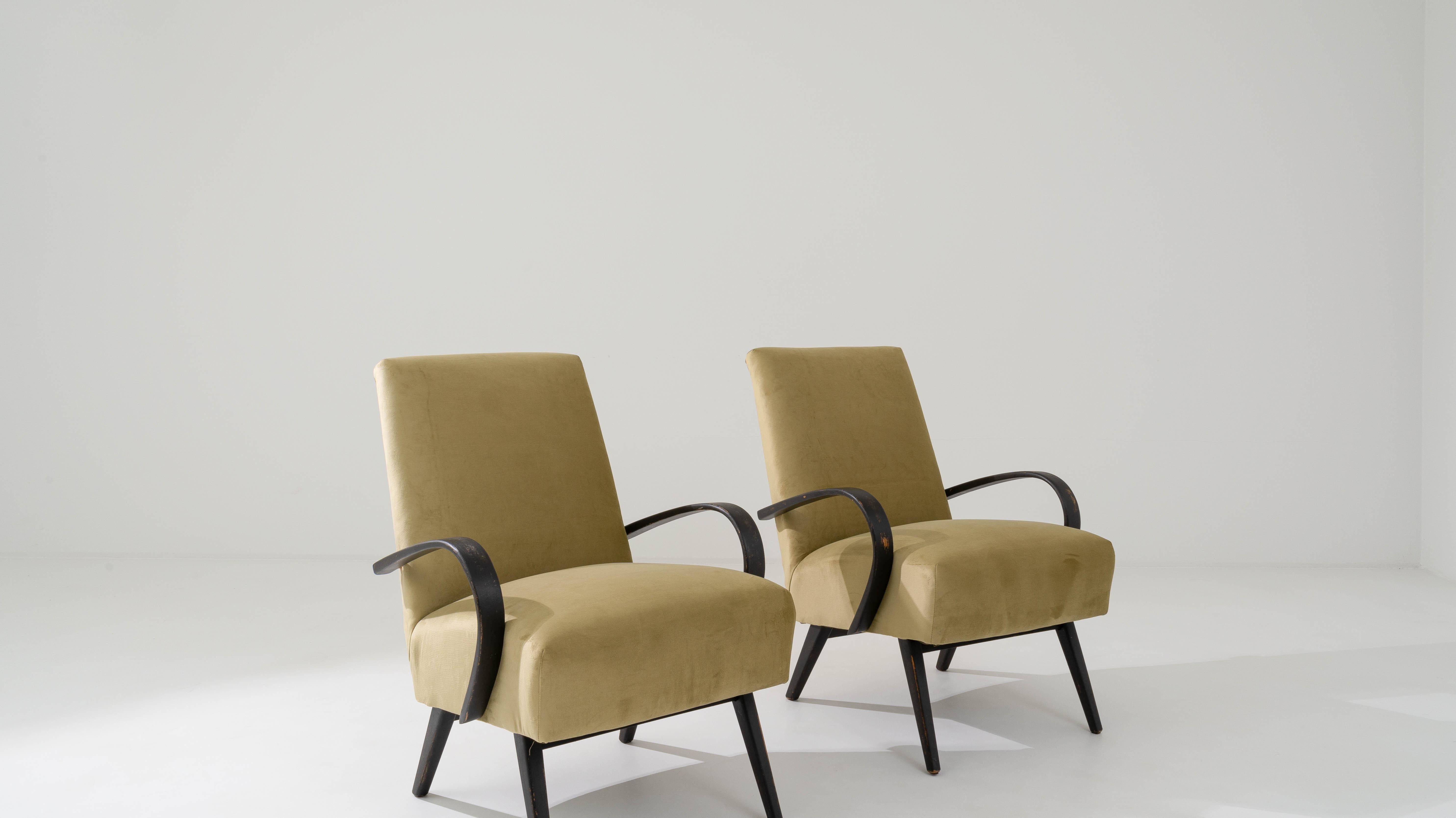 Produced in the former Czechoslovakia, this pair of bentwood armchairs from circa 1950 are re-upholstered with an updated neutral fabric. The velvety upholstery was chosen to compliment the vintage elegance of the black hardwood frame, ochre yellow