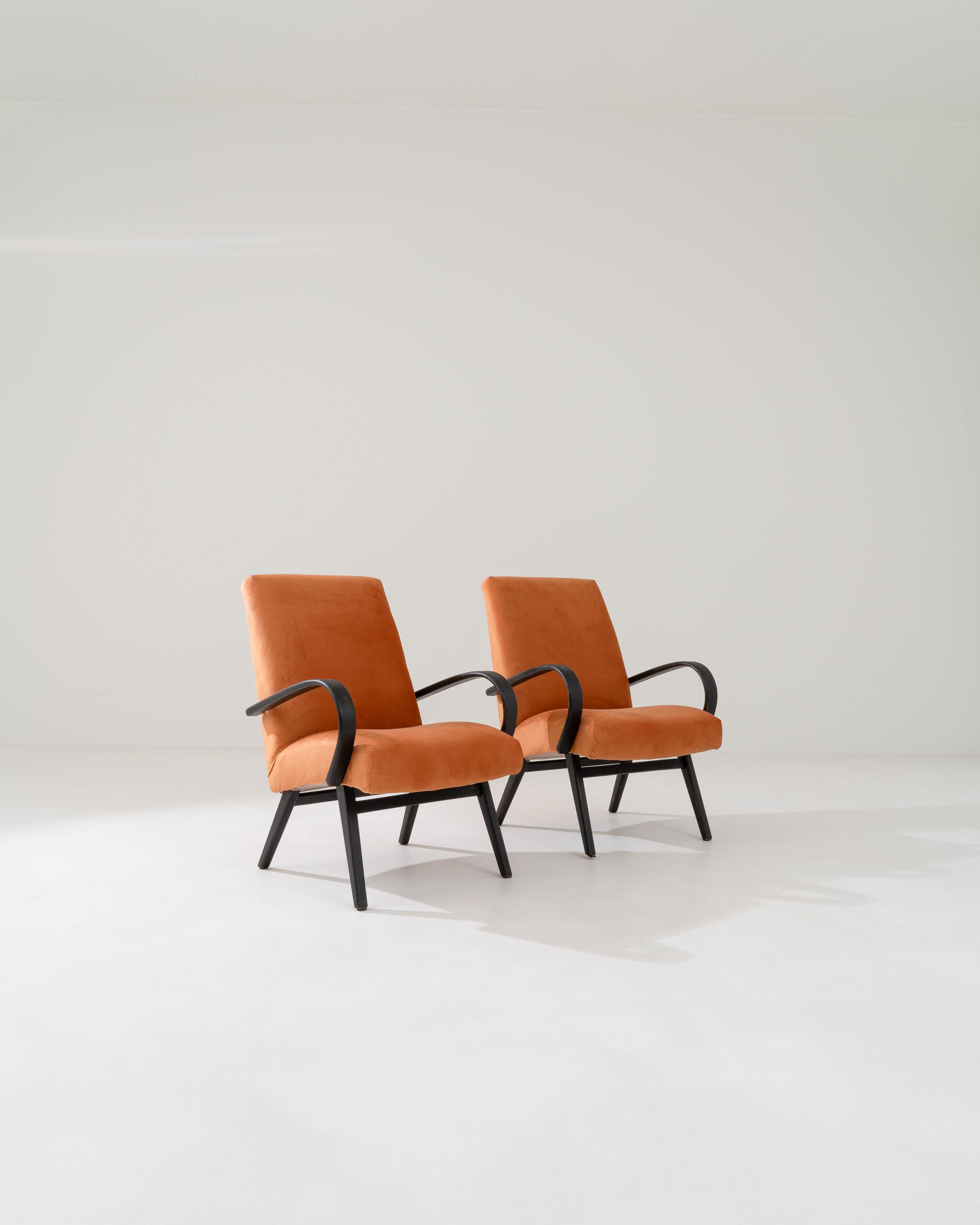 Produced in the former Czechoslovakia, this pair of bentwood armchairs from circa 1950 are re-upholstered with an updated neutral fabric. The velvety upholstery was chosen to compliment the vintage elegance of the black hardwood frame, tangerine
