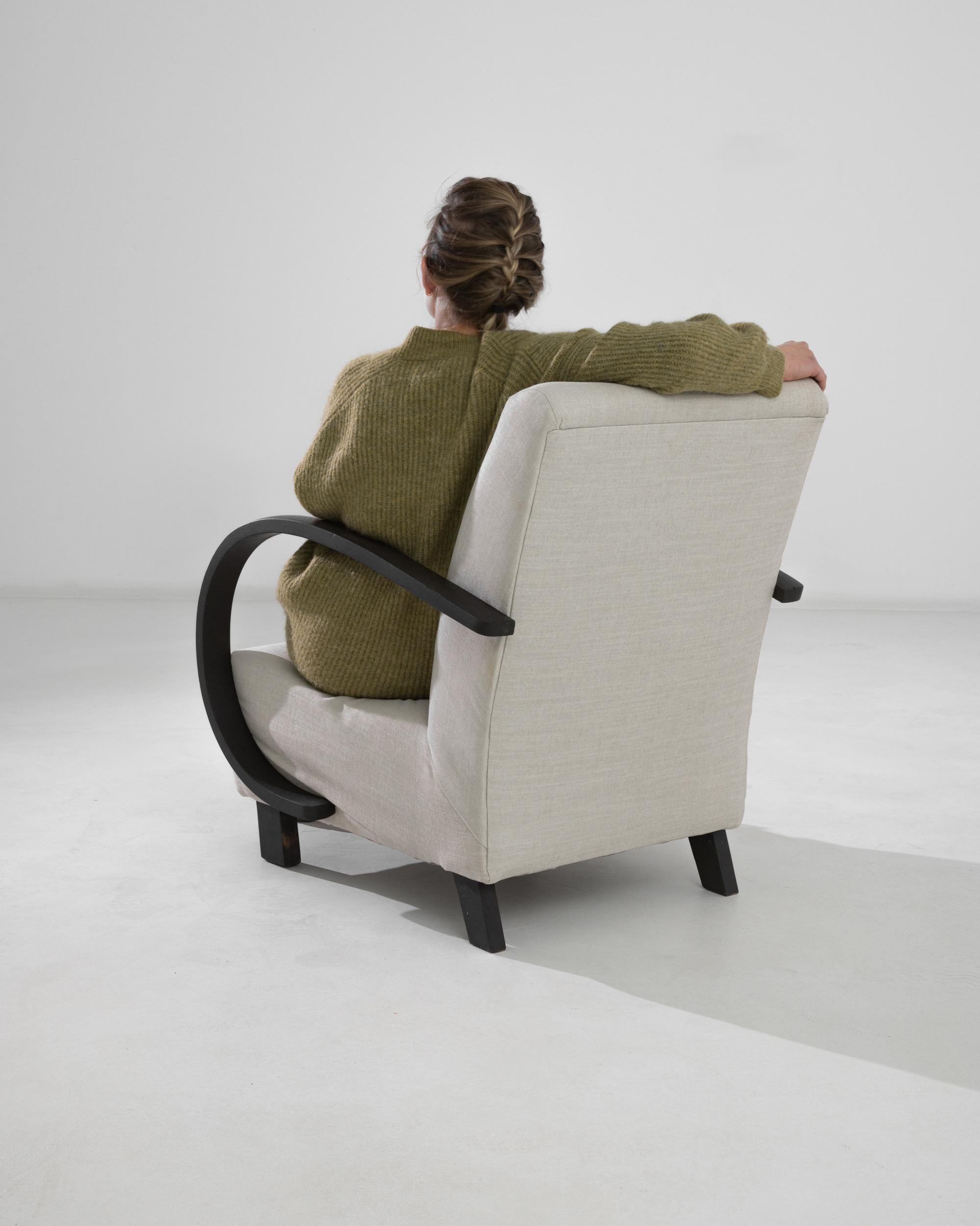 This 1950s Czech Wooden Armchair by J. Halabala is a striking example of early 20th-century modernist design, blending functionality with artistic flair. The armchair is instantly recognizable by its elegantly curved, jet-black wooden arms that