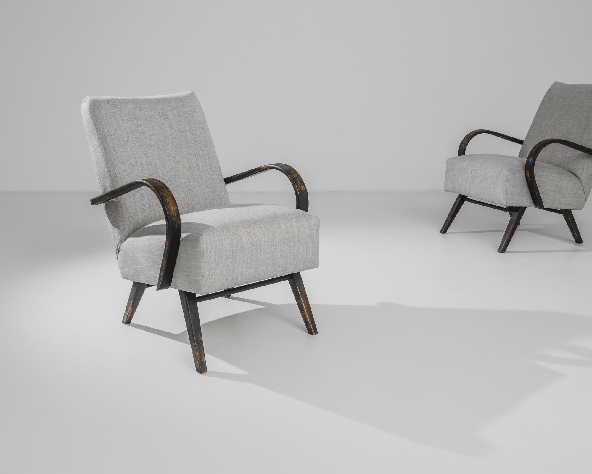 Indulge in mid-century modern design with this exquisite pair of 1950s Czech wooden armchairs by J. Halabala. The chairs showcase Halabala's signature flair for curvaceous forms and functional elegance. The dark, stained wood frames contrast