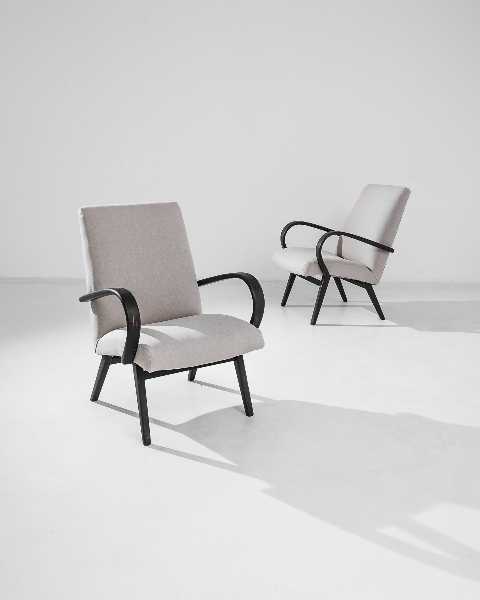Step back into the golden age of mid-century modern design with this pair of 1950s Czech Wooden Armchairs by the iconic Jindřich Halabala. These armchairs are a testament to the timeless elegance of Halabala's work, featuring gracefully curved black