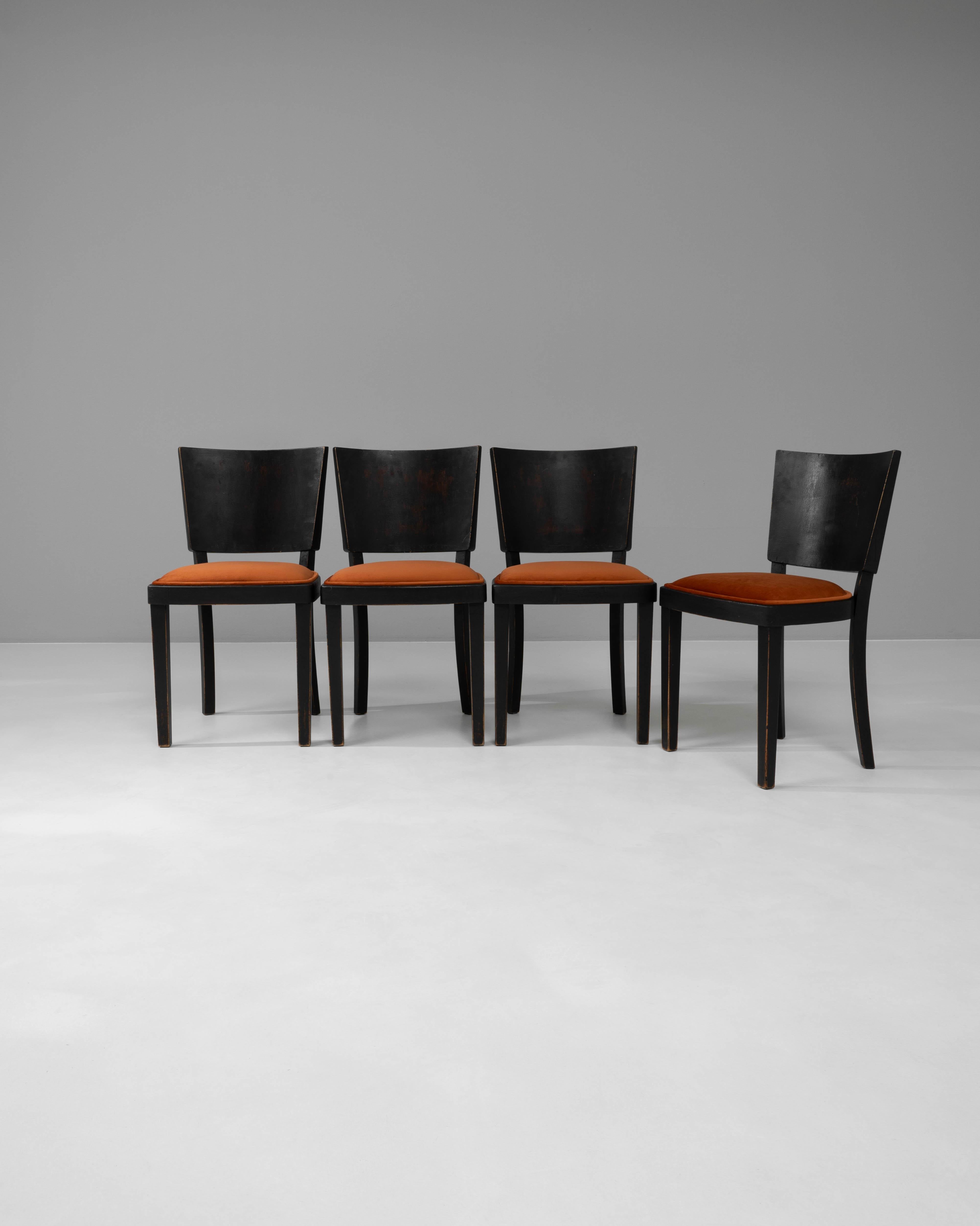 Introduce a touch of mid-century elegance to your dining space with this sophisticated set of four 1950s Czech Wooden Dining Chairs. Each chair features a sleek, dark wooden frame that provides a stark contrast to the vibrant orange upholstered