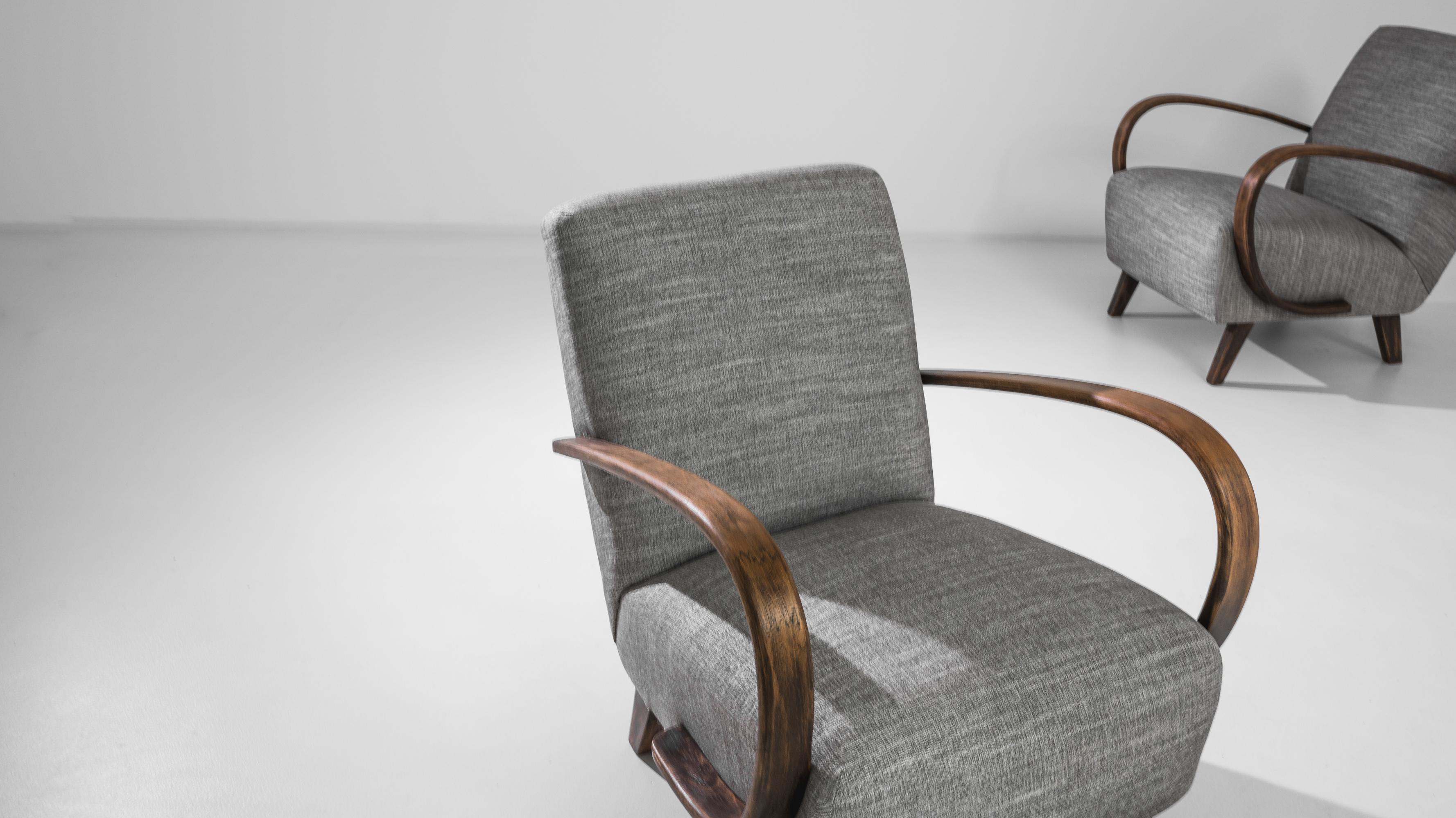 Discover a touch of mid-century charm with this elegant pair of 1950s Czech armchairs by J. Halabala. These pieces showcase the timeless allure of the era's design, featuring a streamlined silhouette with fluid, bentwood armrests that gracefully