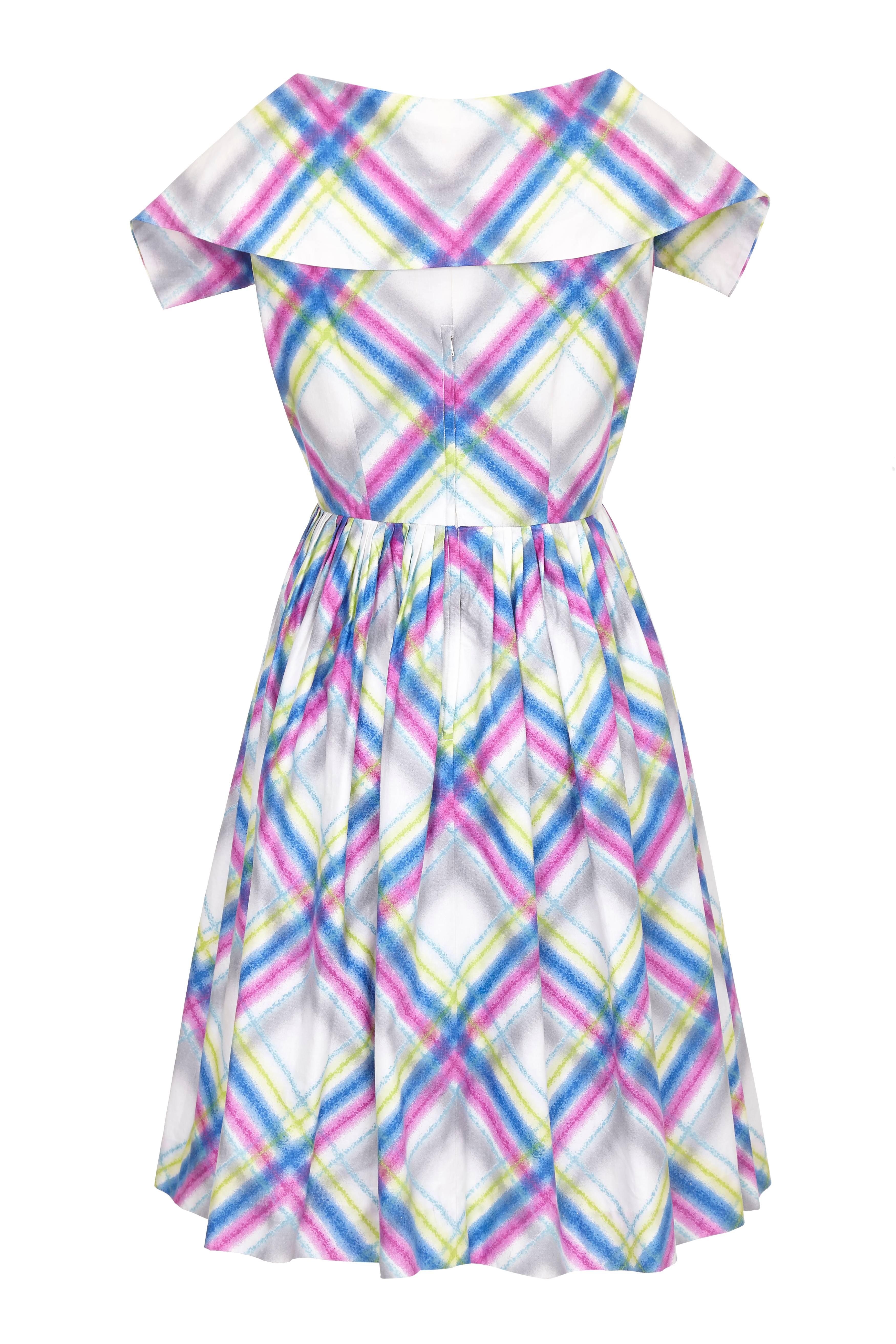 This pretty 1950s cotton dress with a multi-coloured watercolour plaid print features a deep V neckline with a wide collar, wrap-over front and a full pleated calf length skirt. The thick cotton fabric has retained all the vibrancy of print in