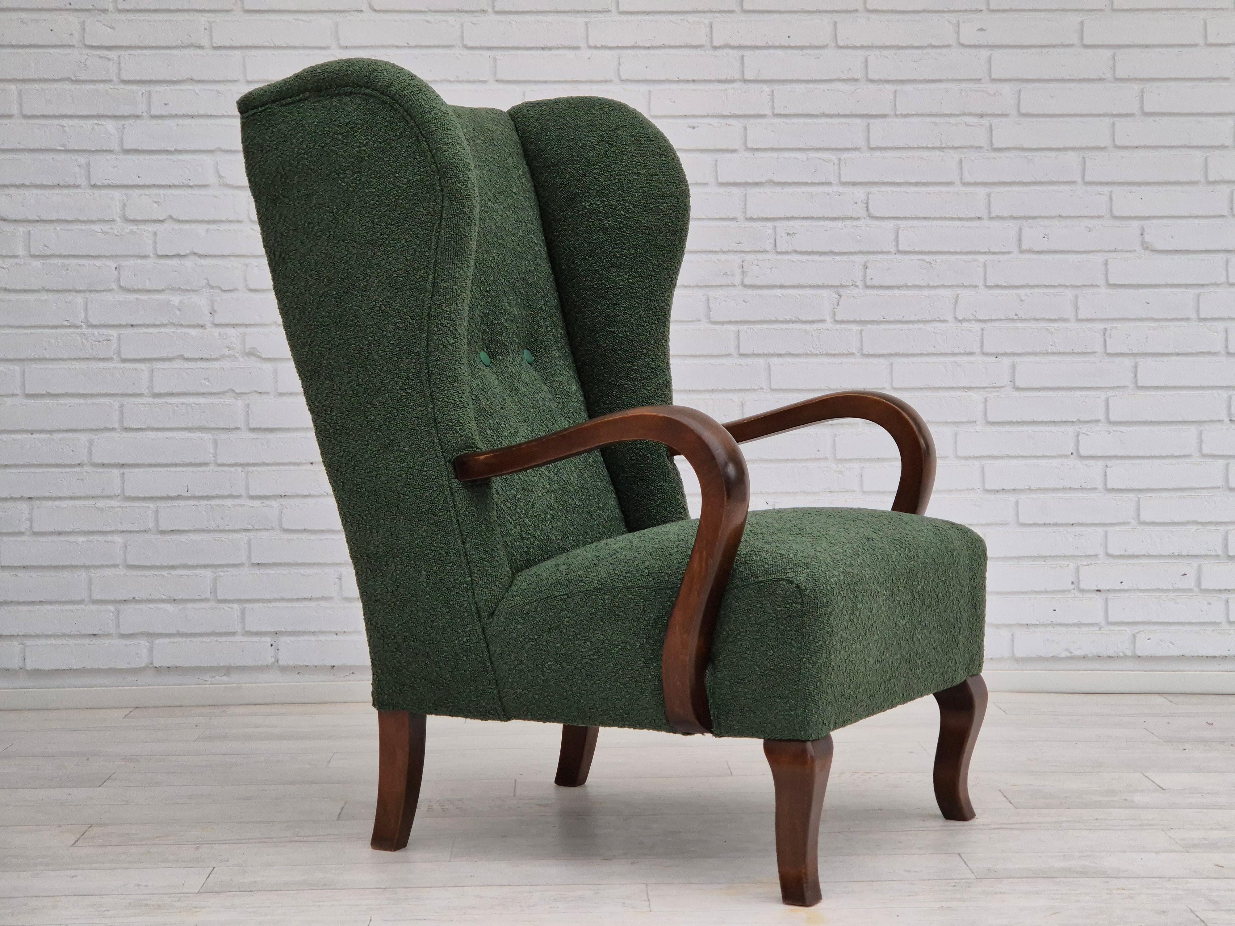 1950s, Danish design. Reupholstered high-back wingback chair in quality bottle green furniture fabric. Faux leather green buttons. Renewed leg and armrest in beech wood. Brass springs in the seat and back. Manufactured by a Danish furniture
