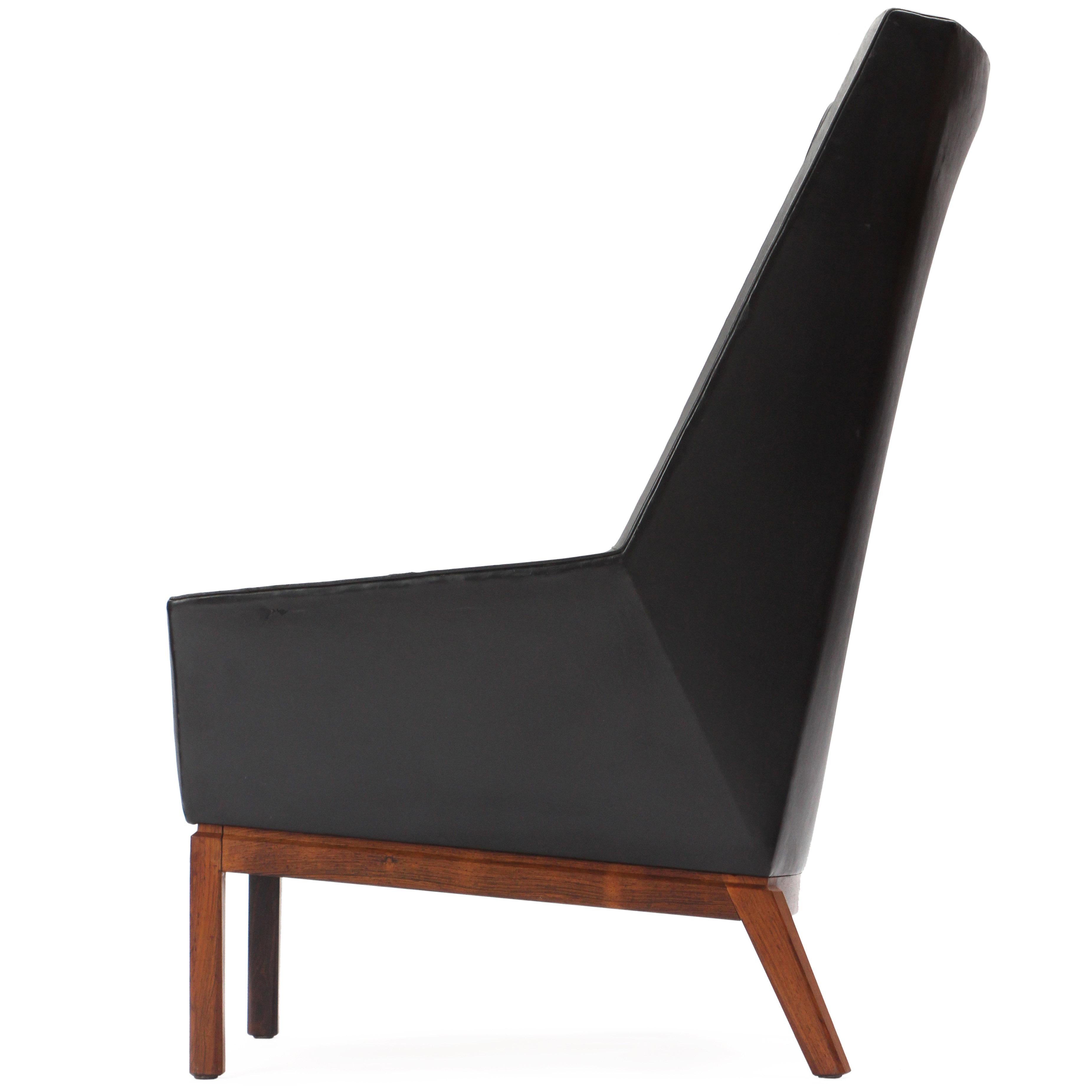 A high back lounge chair in original black leather upholstery with rosewood frame.