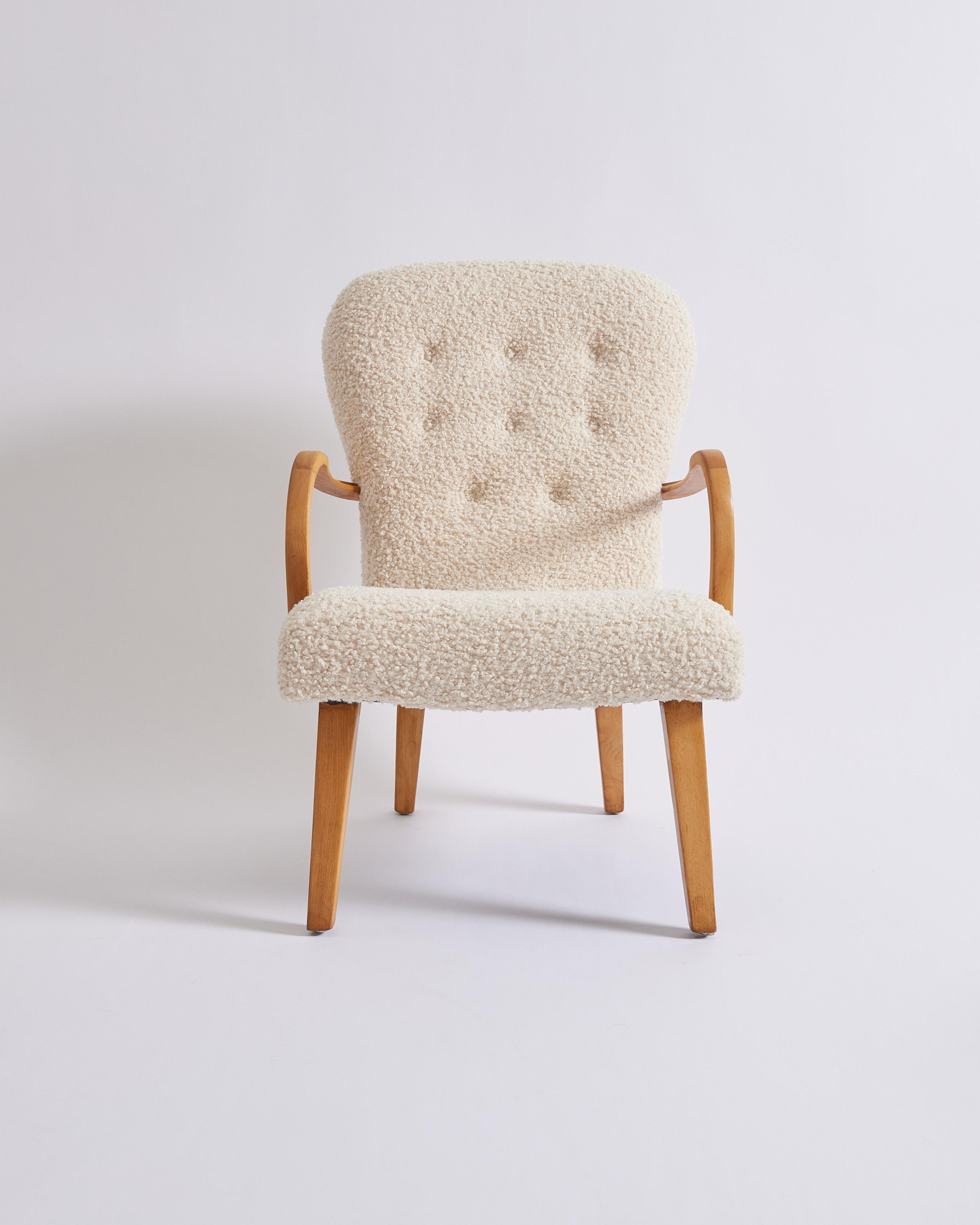 This is a classic Danish Cabinetmaker chair that exemplifies the iconic craftsmanship that mid century Danish furniture is known for. It has been newly reupholstered in a soft and fluffy boucle fabric that resembles sheepskin. The beech legs and