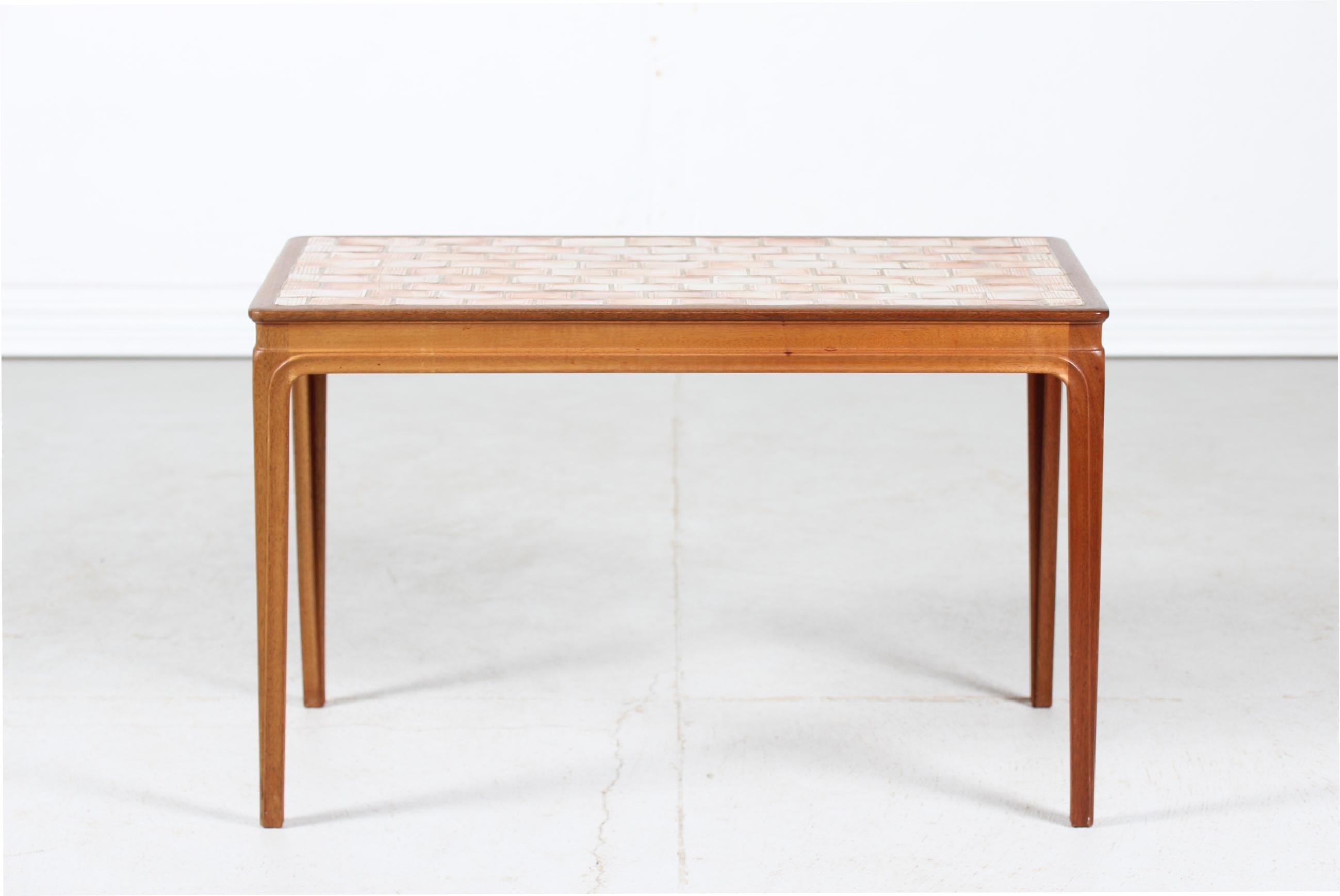 1950s Danish mid-century coffee table made of mahogany with inlaid ceramic tiles in orange-brown colors.
The table is oil treated and manufactured in the 1950´s at cabinet-maker Christian Rasmussen furniture in Randers Denmark.

Nice vintage