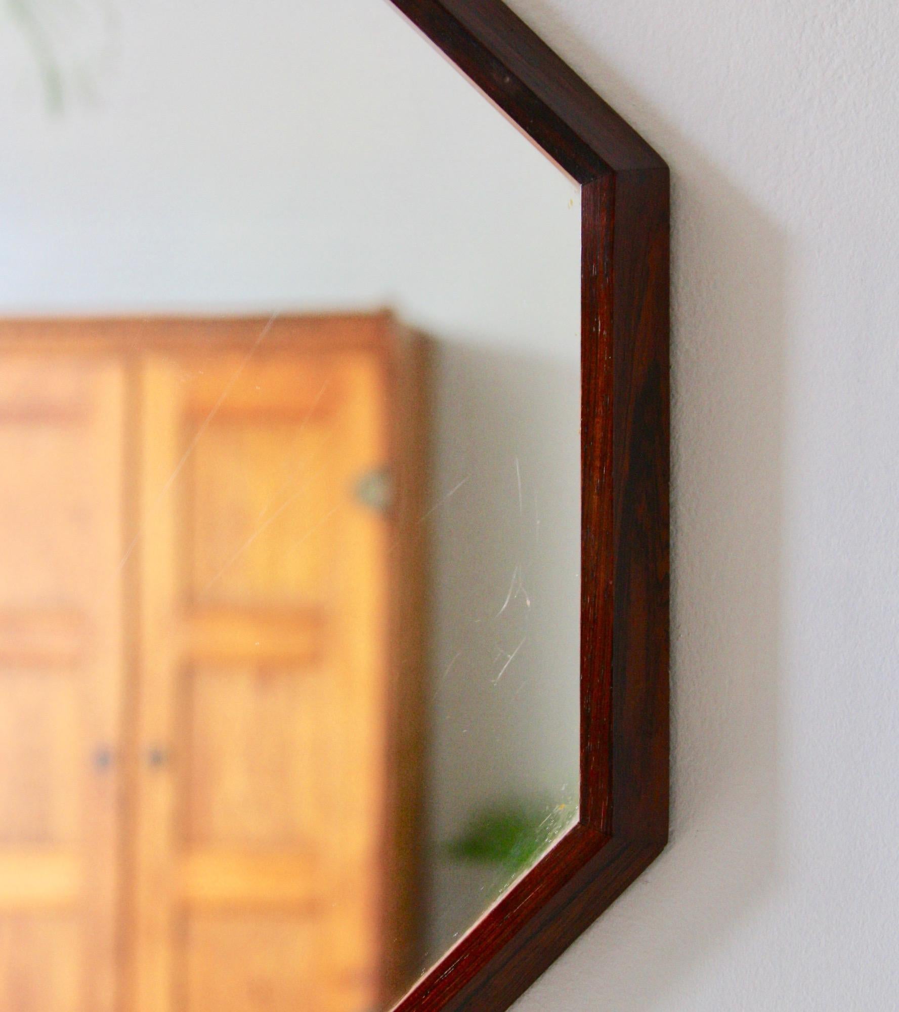 Danish vintage wall mirror dating back to 1950s. With a wooden frame tapered to a point hangs with a metal hook on the back of the frame. The mirror is made of solid rosewood. In excellent condition.
  