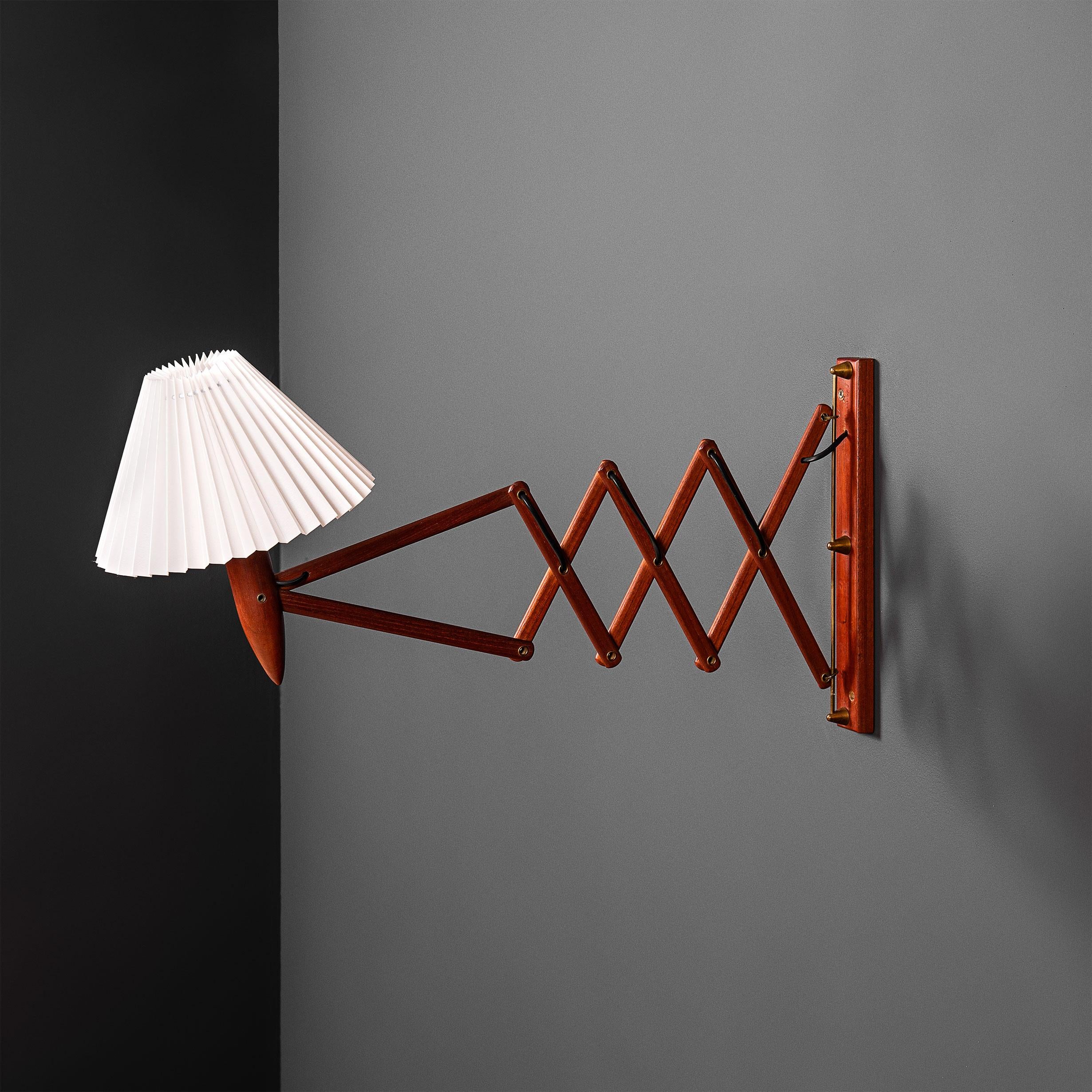 A 1950's Danish teak and brass scissor/extending wall lamp. 2 available. Push/pull and left/right movement. The shade component can also slightly adjust. Produced in Denmark circa 1950. Produces a superb light. Currently wired with a cable to wall